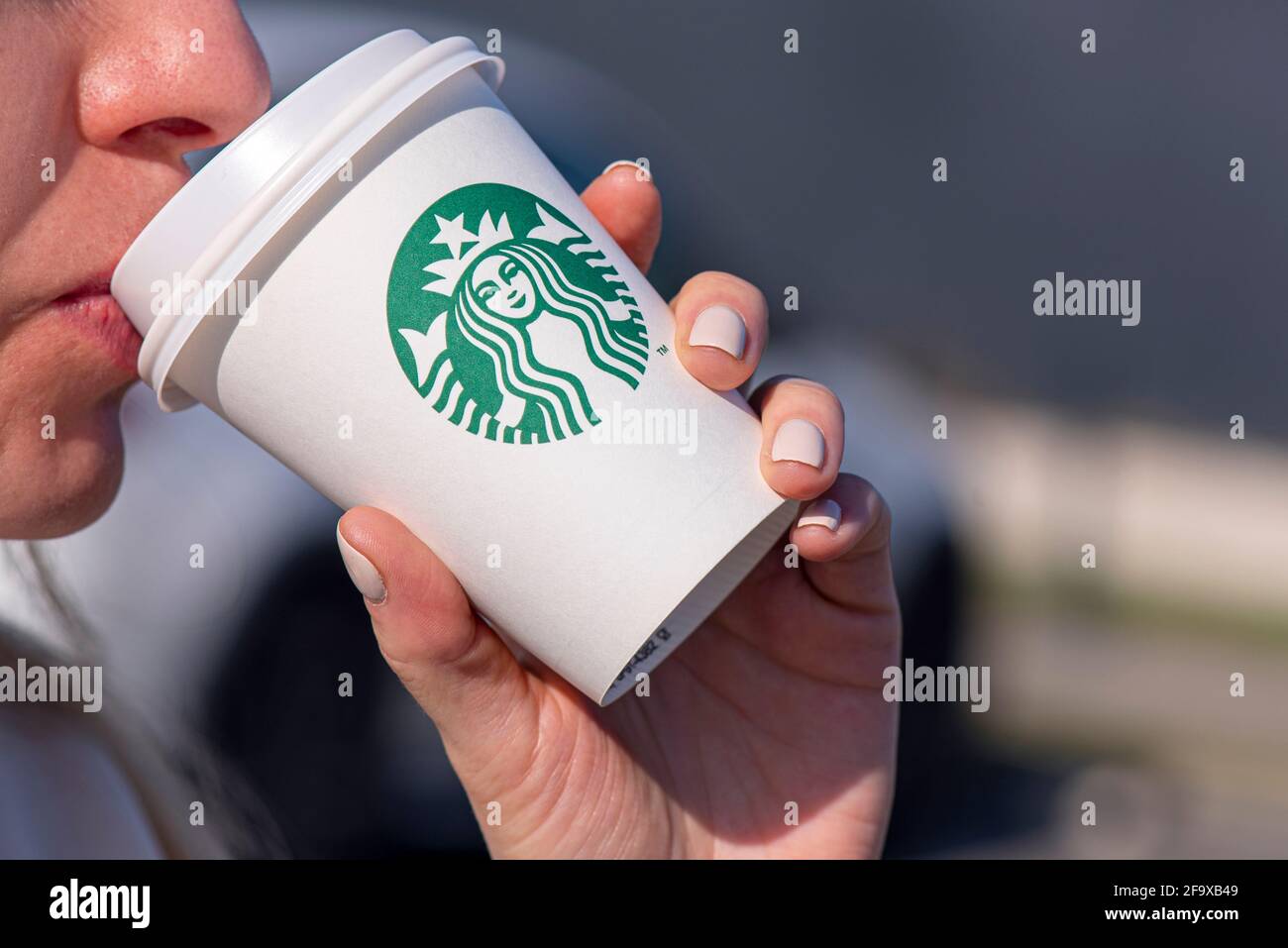 BERLIN - APR 17: Une femme tenant une coupe en papier avec le logo Starbucks dans une rue de Berlin, avril 17. 2021 en Allemagne Banque D'Images