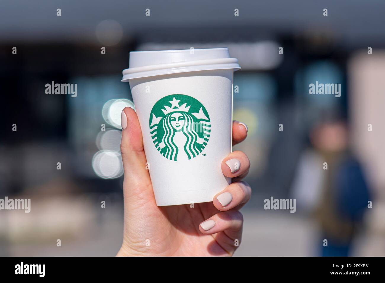 BERLIN - APR 17: Une femme tenant une coupe en papier avec le logo Starbucks dans une rue de Berlin, avril 17. 2021 en Allemagne Banque D'Images