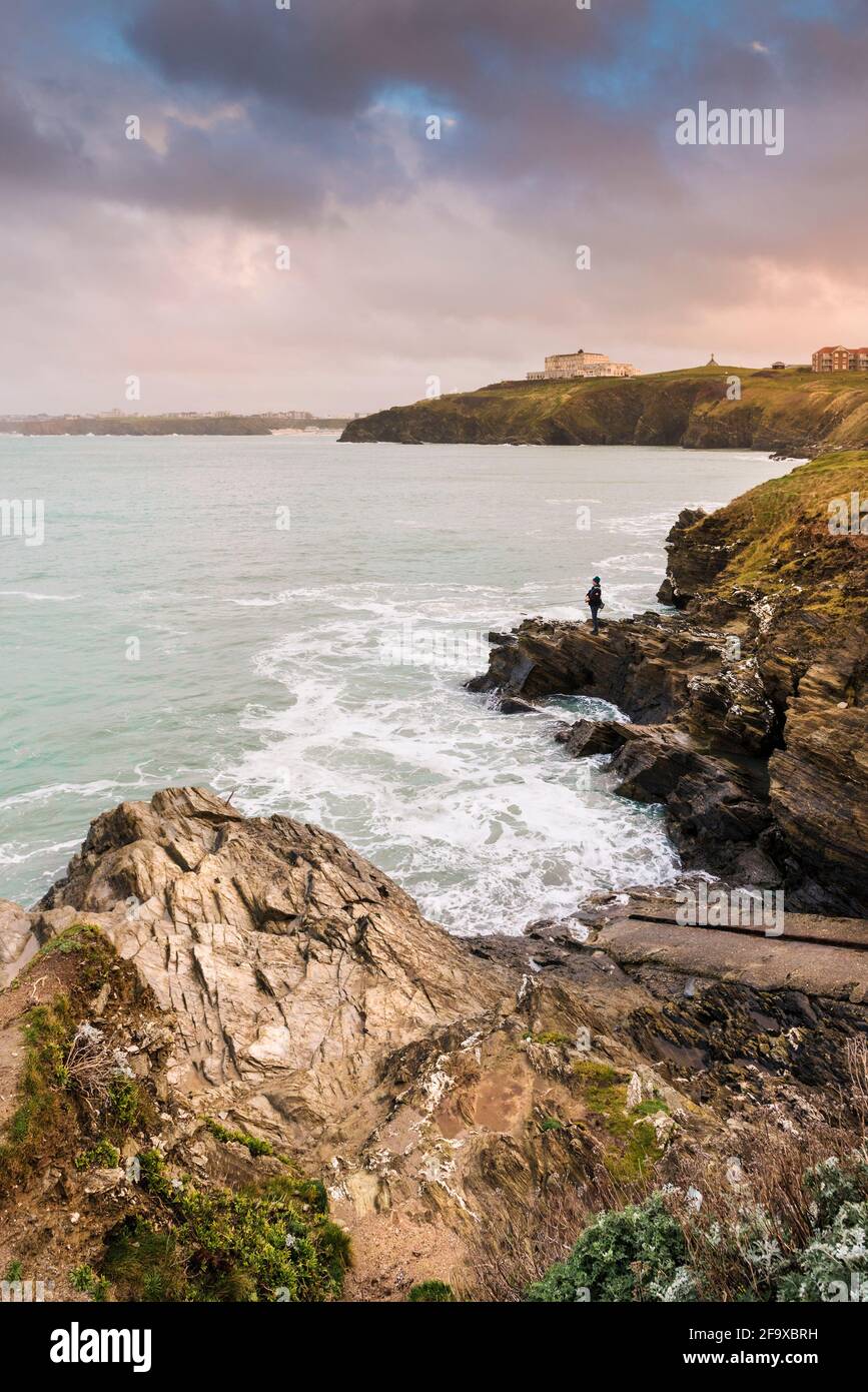 Lumière chaude en soirée au-dessus d'un pêcheur à la ligne pêchant au large des rochers sur la côte de la baie de Newquay, dans les Cornouailles. Banque D'Images
