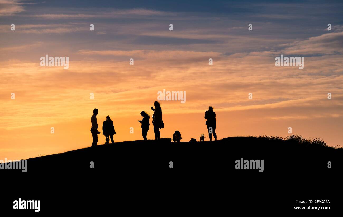 Une image panoramique des randonneurs se tenant sur Penentire point East et silhoueté par un coucher de soleil spectaculaire à Newquay en Cornouailles. Banque D'Images