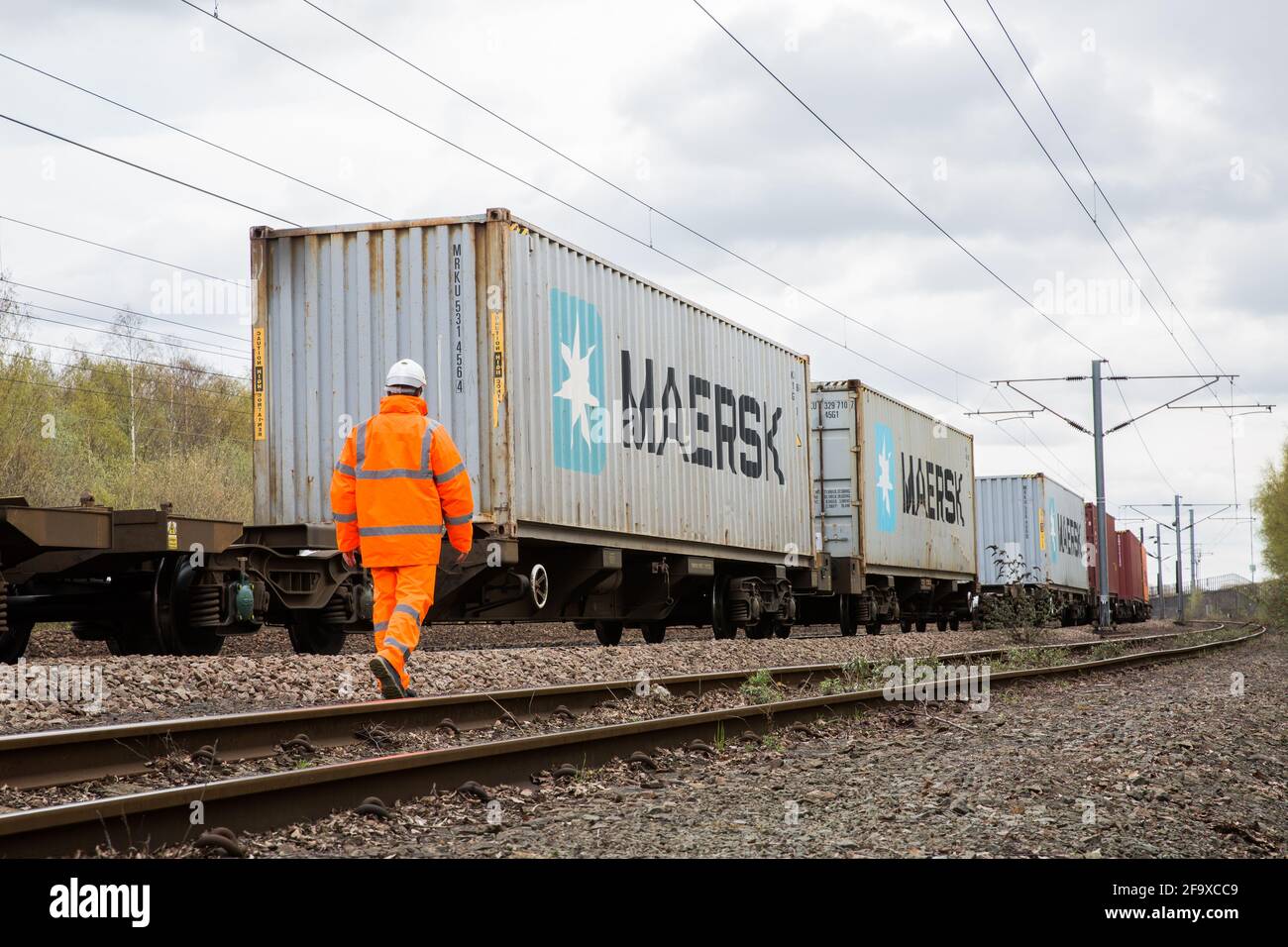 DONCASTER, ROYAUME-UNI - 4 AVRIL 2021. Un travailleur ferroviaire inspectant un train de marchandises à conteneurs d'expédition Maersk sur le réseau ferroviaire britannique avant l'exportation ou l'importation. Banque D'Images