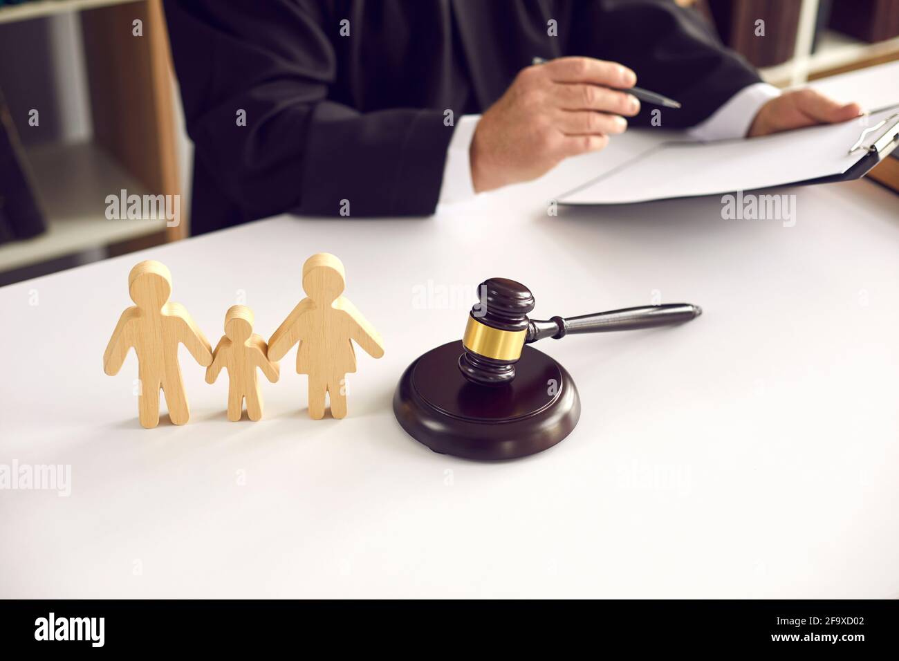Figurines de famille en bois et gavage sur fond de juge qui signe une sentence. Banque D'Images