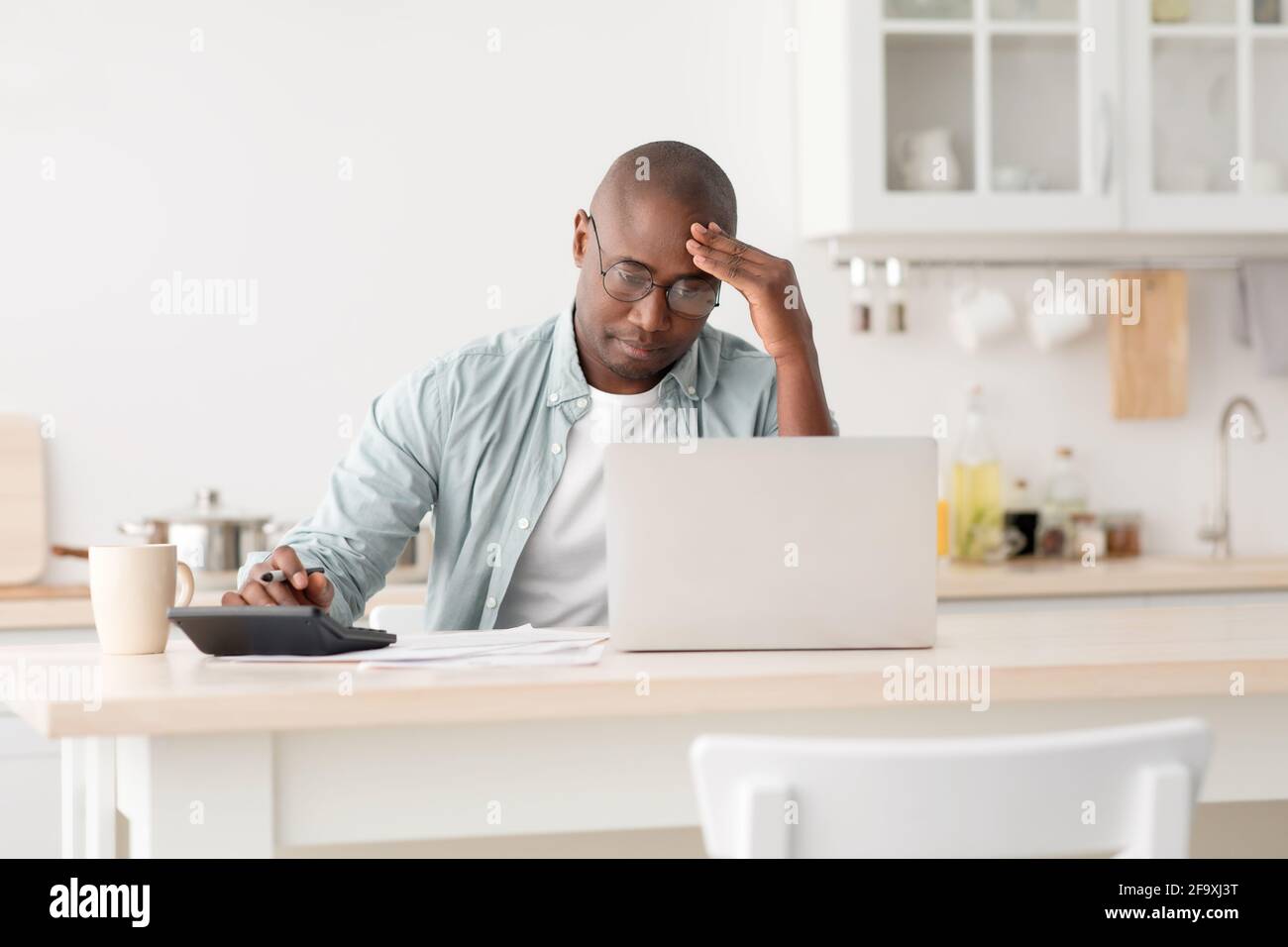 Homme noir mature stressé utilisant la calculatrice et ordinateur portable, le calcul des taxes, le contrôle des dépenses mensuelles Banque D'Images