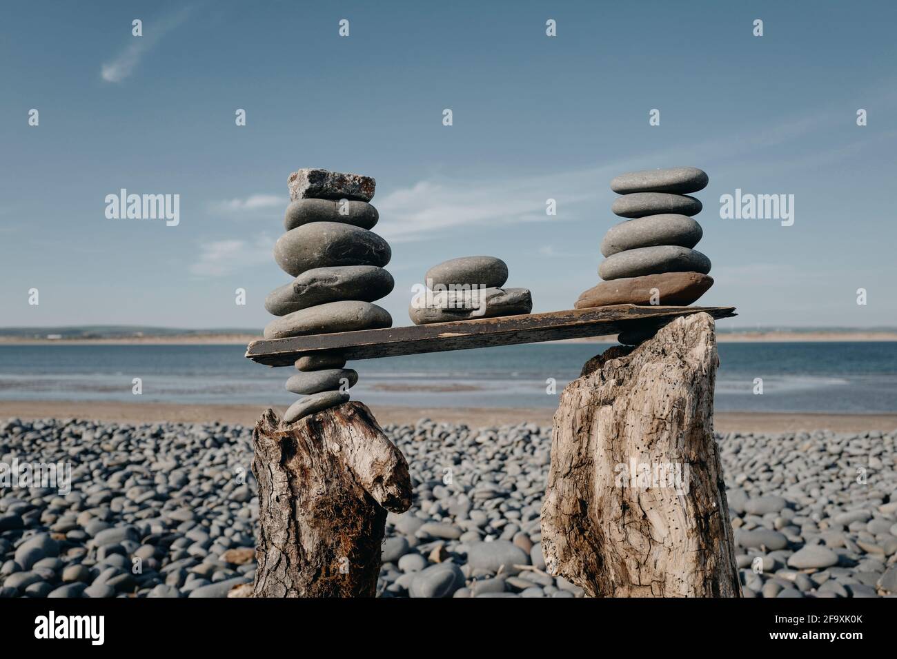 Une sculpture sur la plage d'une tour de galets empilés sur du bois flotté à Westward Ho!beach, Devon, Royaume-Uni Banque D'Images