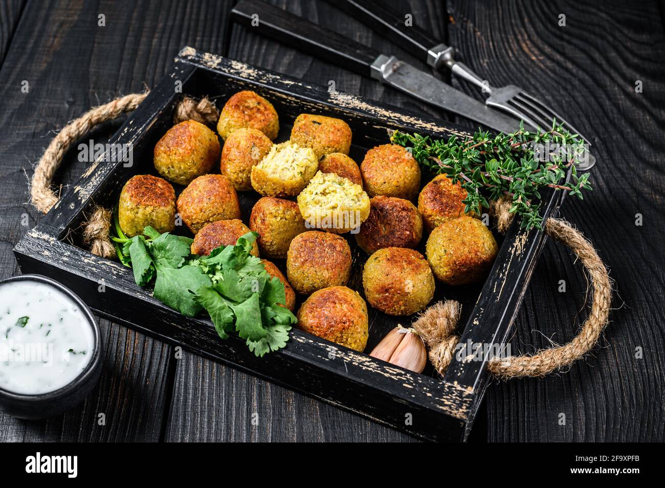Boulettes de falafel de pois chiches rôtis avec sauce au yogourt à l'ail dans un plateau en bois fond noir. Vue de dessus Banque D'Images