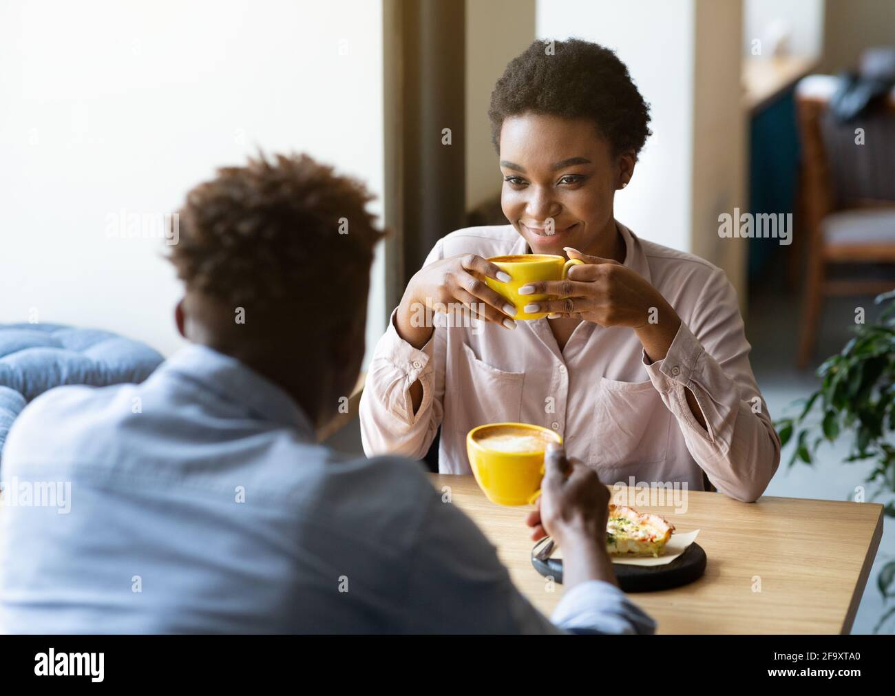 Beau noir homme avec sa petite amie appréciant le café aromatique et avoir une conversation amicale au café de la ville Banque D'Images