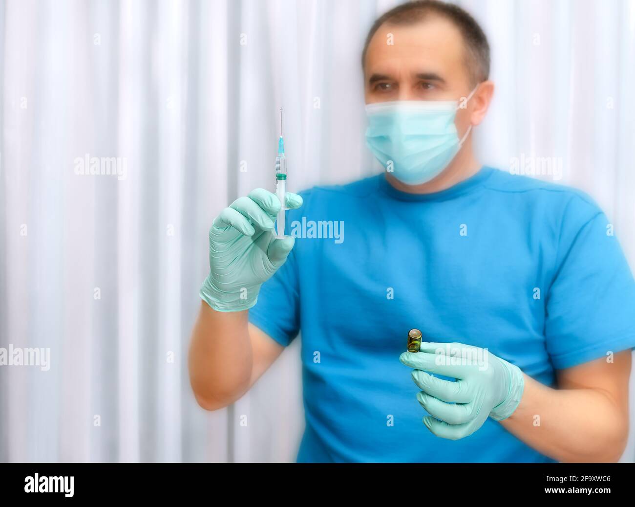 Les mains du médecin en gants bleus avec une seringue et un flacon de vaccin ou de médicament Banque D'Images