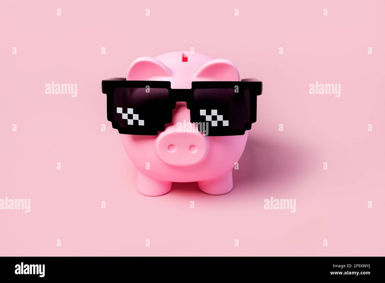 Banque d'argent de porc rose avec des lunettes de soleil noires sur un rose arrière-plan Banque D'Images