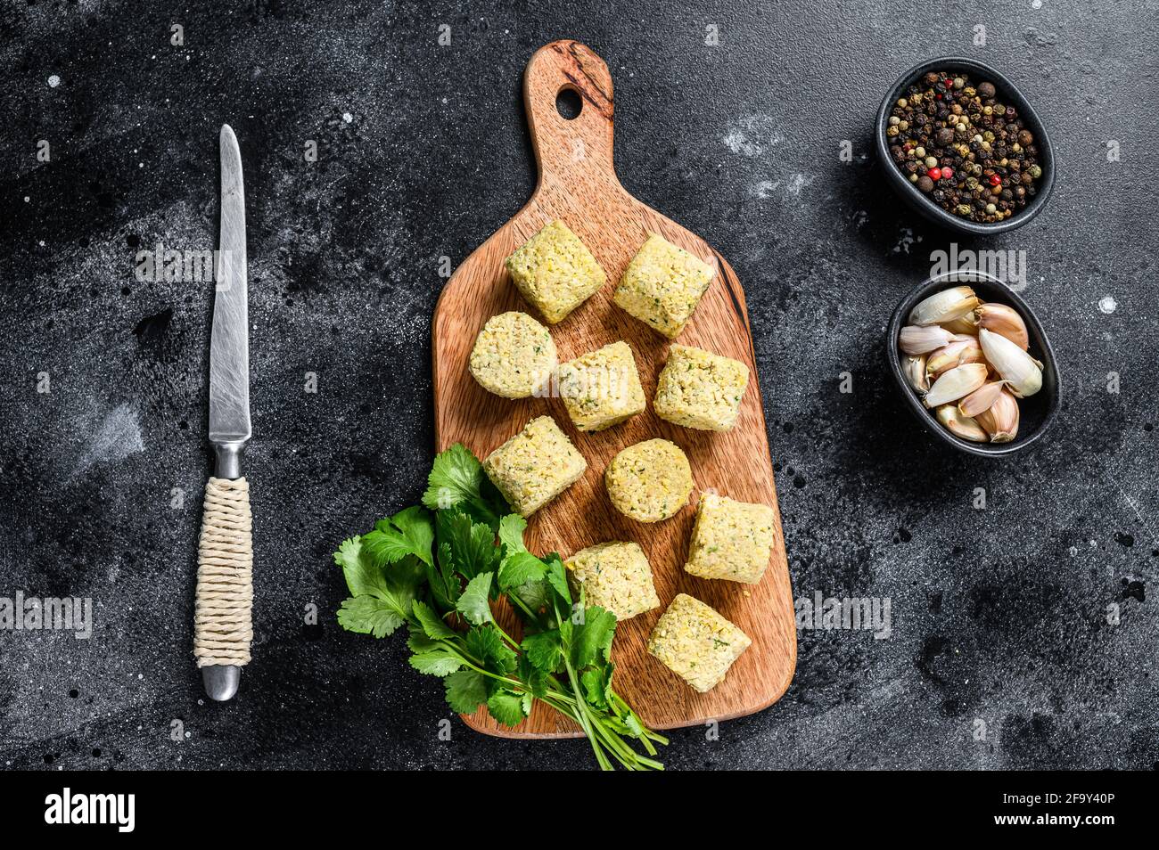 Billes de falafel brutes sur une planche à découper en bois. Arrière-plan noir. Vue de dessus Banque D'Images