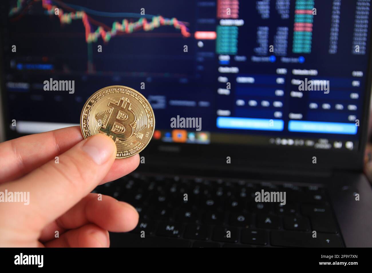 Homme tenant une version physique de Bitcoin BTC. En arrière-plan est l'analyse des données dans le marché boursier. Banque D'Images