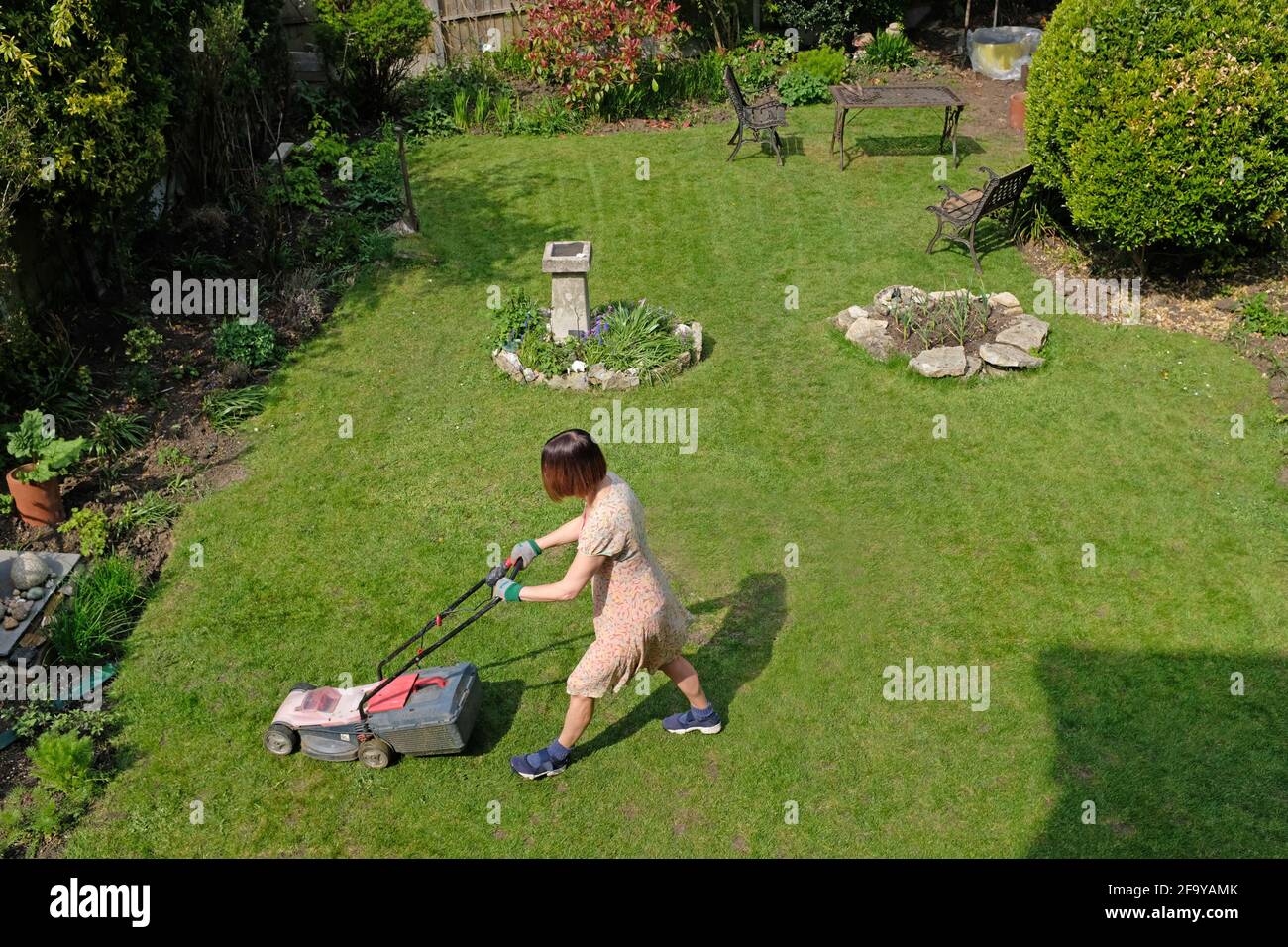 Une femme melle son jardin de banlieue. Vue de dessus. Banque D'Images