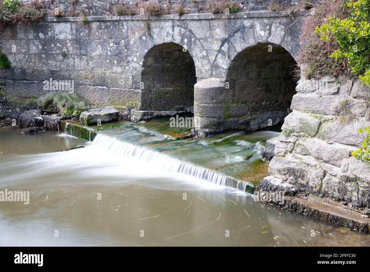 La rivière Helford coule sous un vieux pont en pierre à Gweek, dans les Cornouailles Banque D'Images