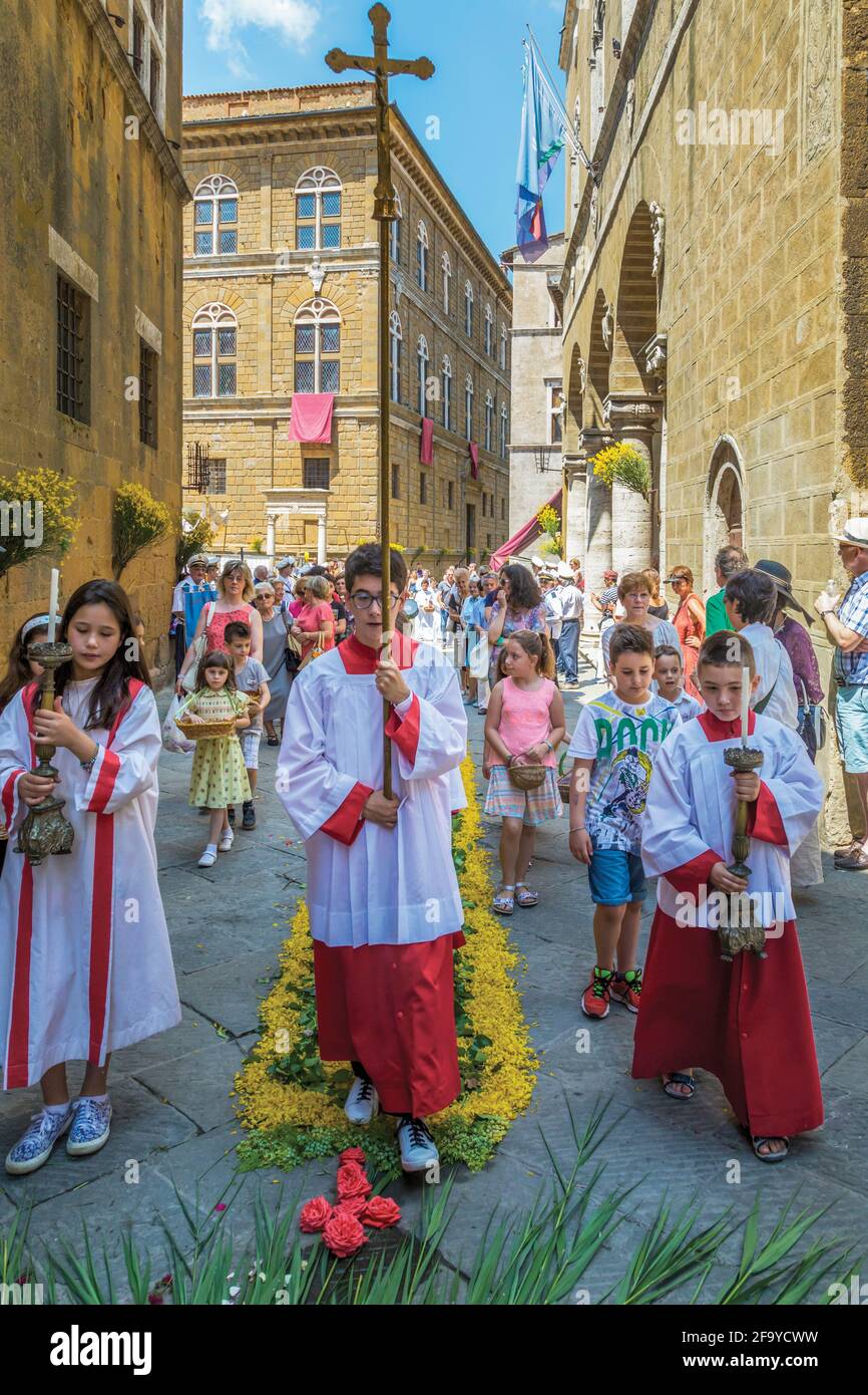 Pienza, province de Sienne, Toscane, Italie. Corpus Christi procession avec de jeunes dévotés transportant des régalia. Le centre historique de la ville de Pienza est Banque D'Images