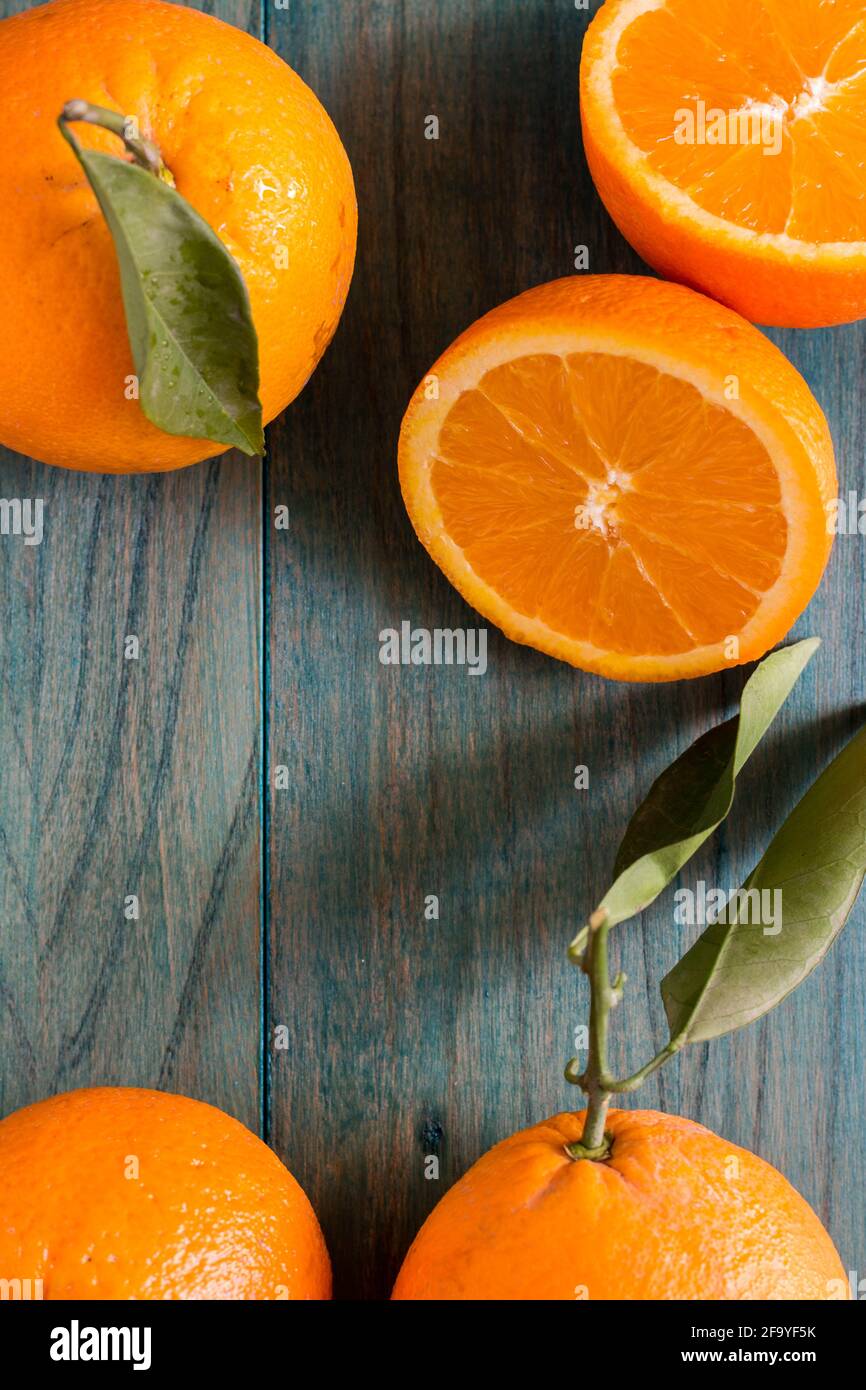 Orange coupé en deux et autres oranges de couleur outremer arrière-plan en bois Banque D'Images
