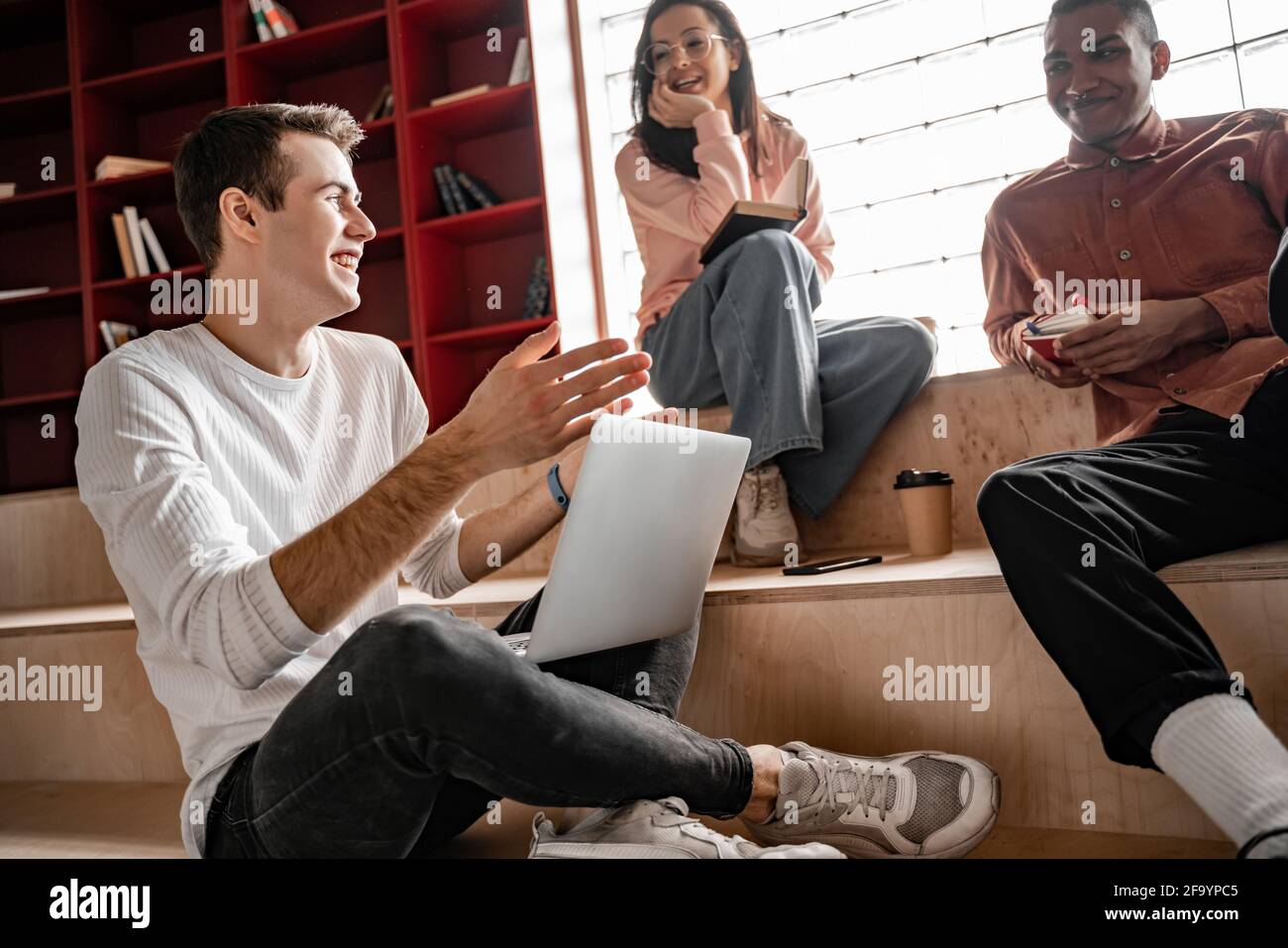 heureux étudiants interraciaux souriant assis dans les escaliers, 2021 ans Banque D'Images