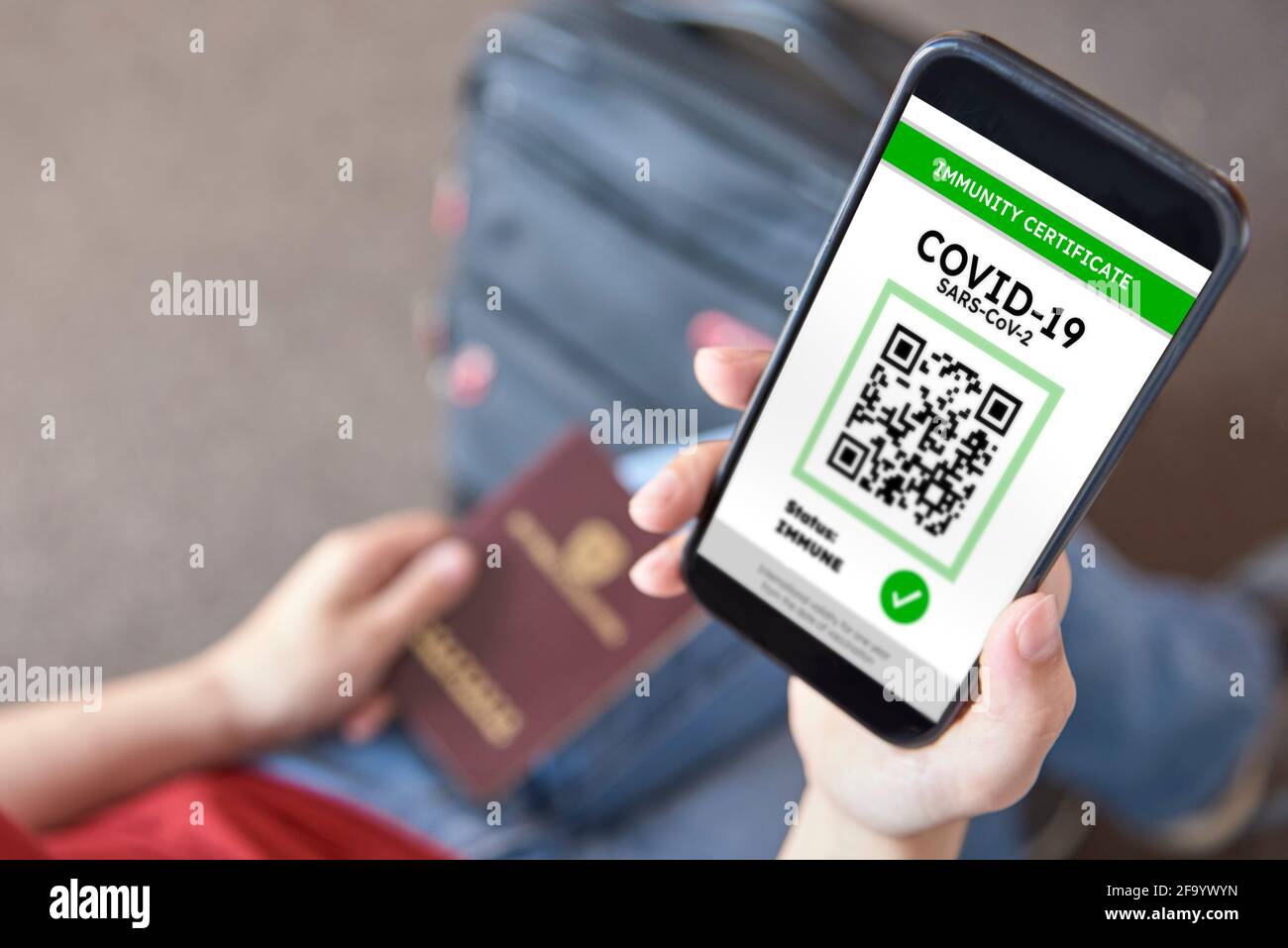Jeune femme méconnaissable sur le point de voyager, portant un smartphone avec un certificat d'immunité contre Covid19. D'autre part, elle tient un passphor Banque D'Images