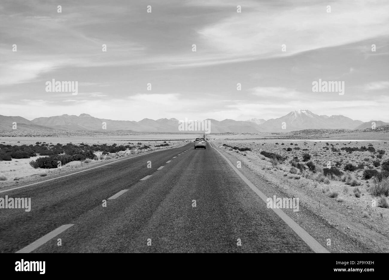 Monochrome d'une voiture roulant sur la route du désert du nord du Chili, en Amérique du Sud Banque D'Images