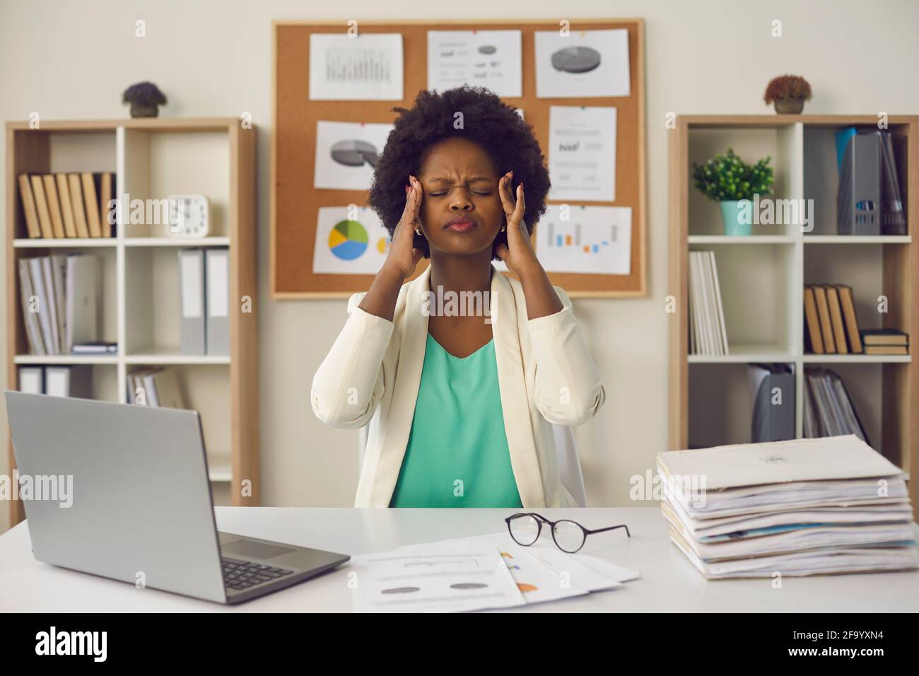 Femme d'affaires afro-américaine frottant des temples assis au bureau portrait Banque D'Images