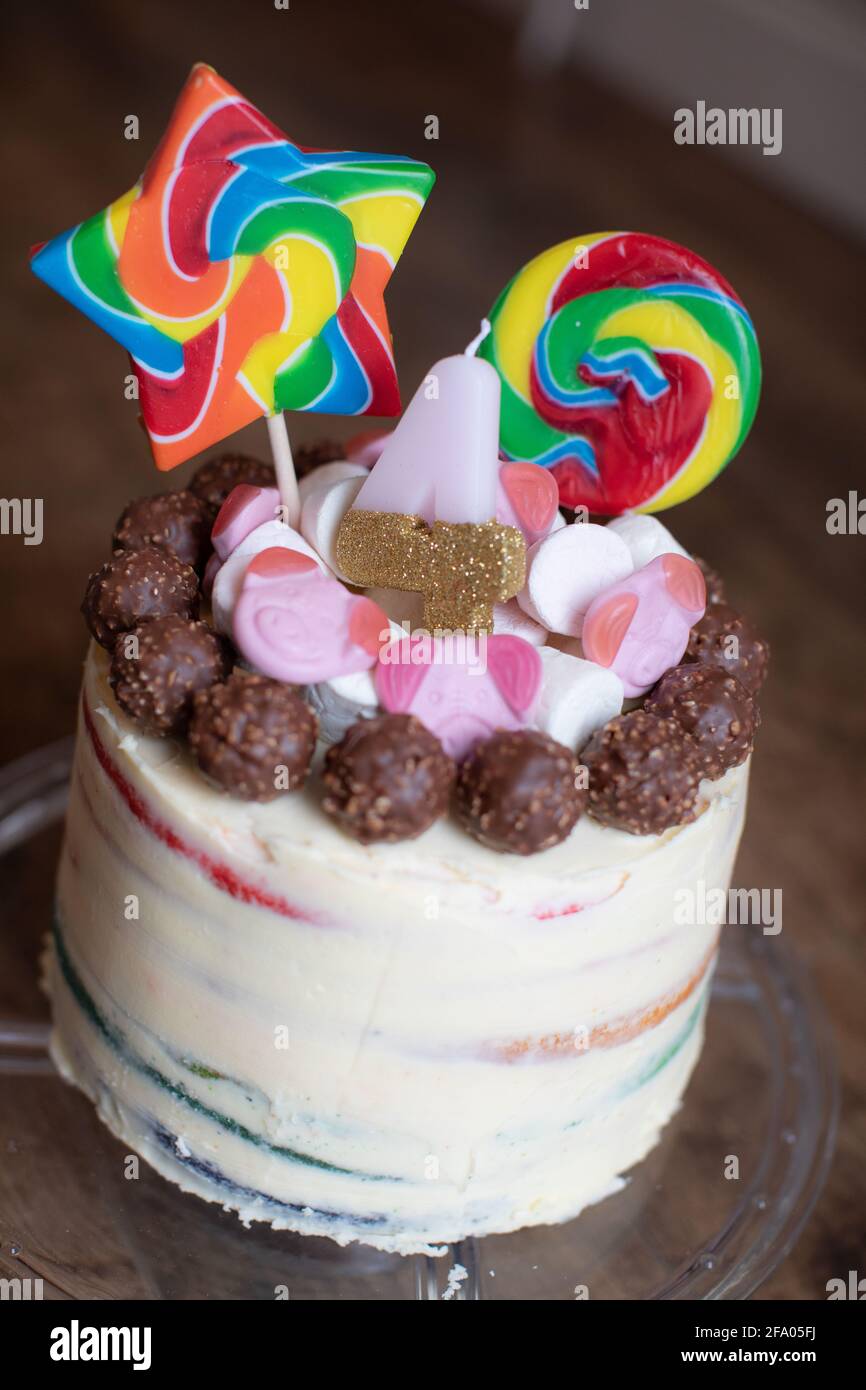 Un gâteau d'anniversaire avec des llupops arc-en-ciel pour un enfant de 4 ans. Banque D'Images