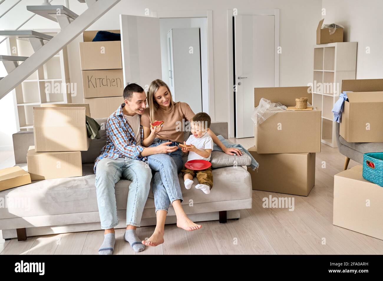 Une famille heureuse avec un enfant assis sur un canapé à la maison lors d'une journée de déménagement. Banque D'Images