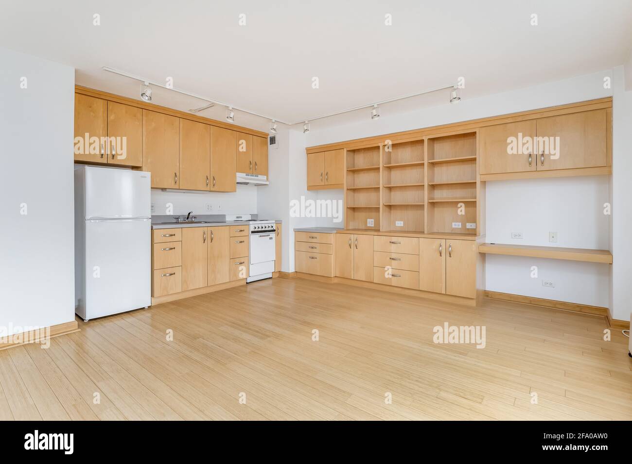 Une cuisine en érable dans un appartement vide de la ville avec des appareils électroménagers blancs, des comptoirs en granit, beaucoup d'armoires pour le stockage, et des planchers de bois franc. Banque D'Images