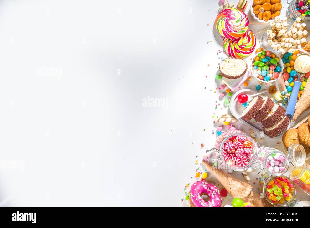 Sélection de bonbons colorés. Assortiment de bonbons, chocolats, beignets, biscuits, sucettes, vue de dessus de crème glacée sur fond blanc Banque D'Images