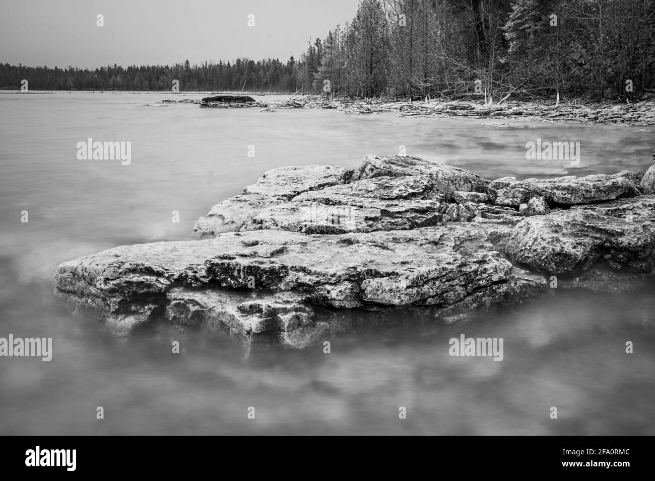 Une ligne de rivage escarpée le long du lac Michigan dans le comté de Door, Wisconsin, photographiée comme une longue exposition noire et blanche lors d'un après-midi de printemps brumeux. Banque D'Images