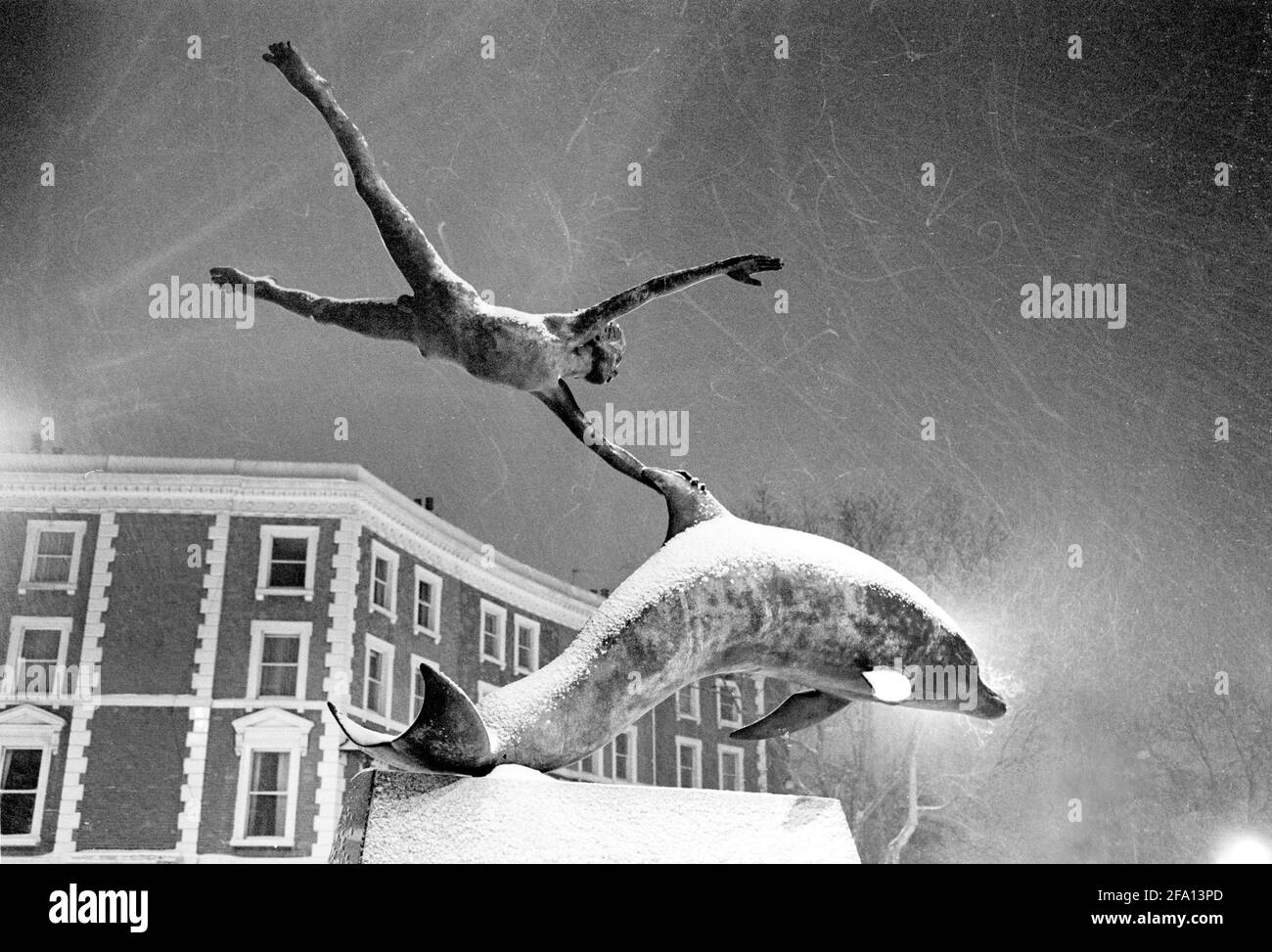 « Boy with Dolphin » - sculpture en bronze de David Wynne - une nuit enneigée en janvier 1982. Oakley Street, Londres. Banque D'Images