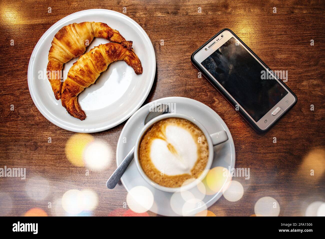 Latte café avec croissants gras et téléphone portable. Banque D'Images