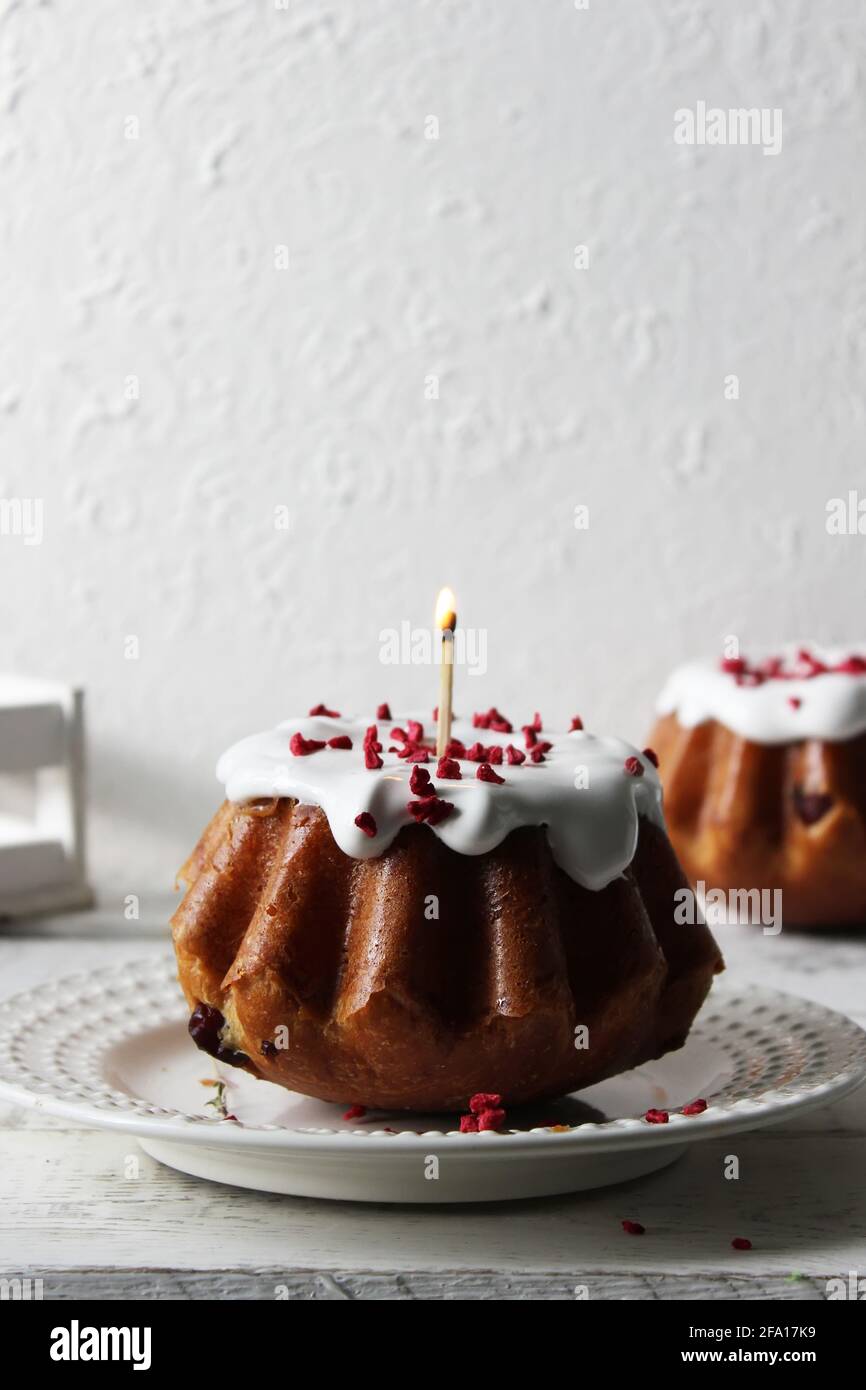 baba de rhum versé avec du glaçage blanc sur une assiette sur une table recouverte d'une nappe blanche. Gros plan. Banque D'Images