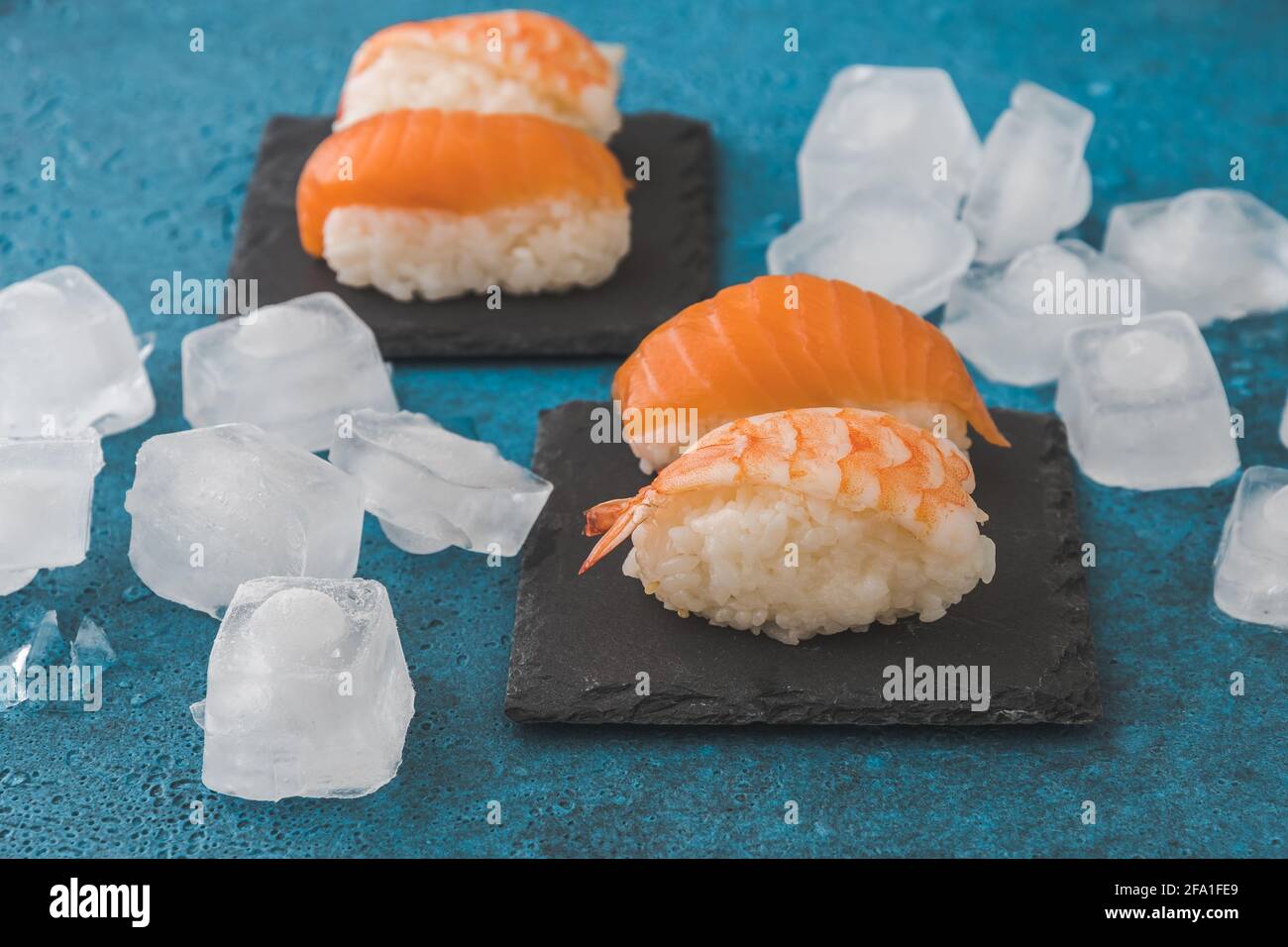 Sushi nigiri sur ardoise avec glaçons sur fond bleu Banque D'Images