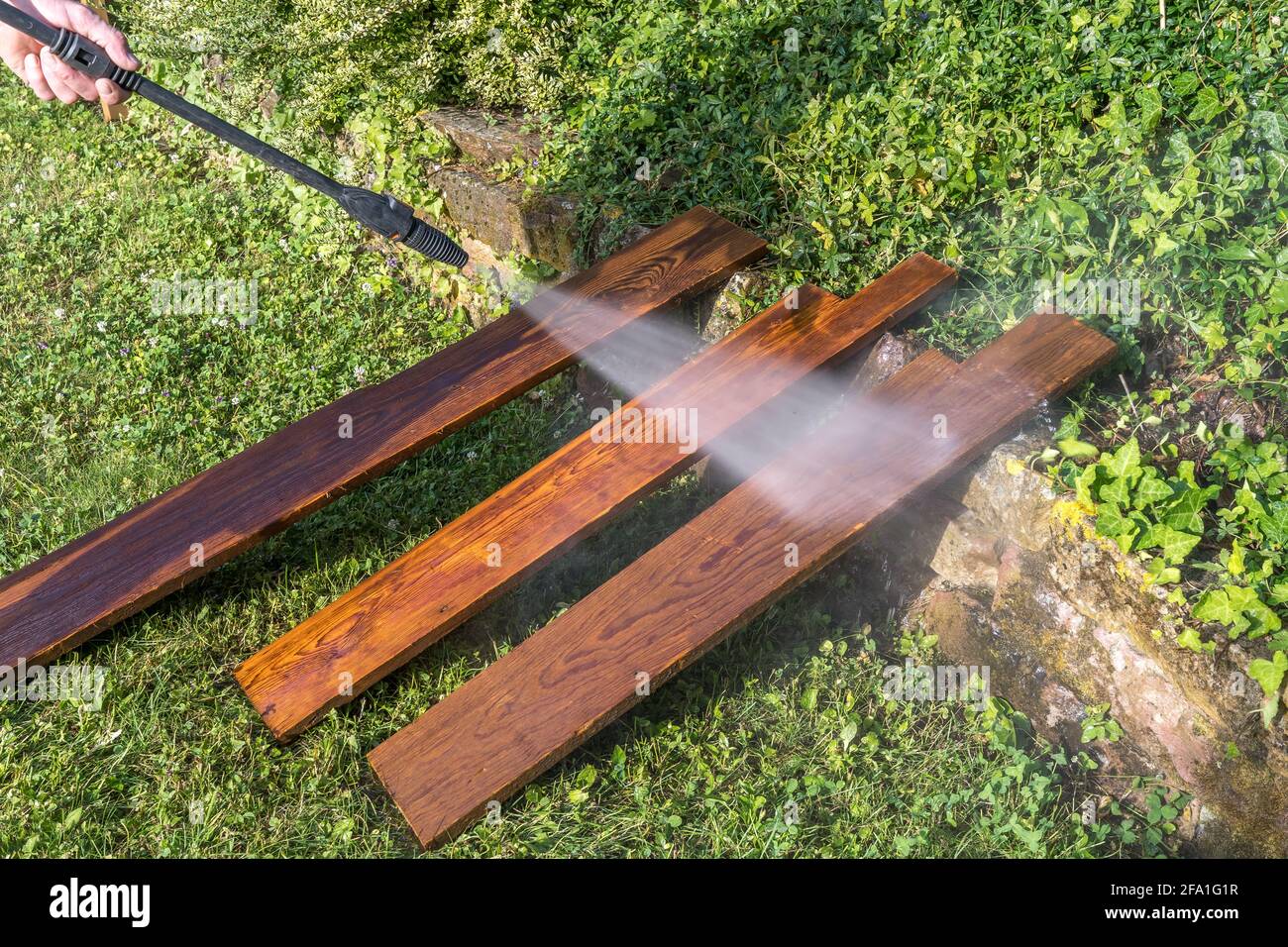 Nettoyage de trois anciennes planches de bois avec un nettoyeur haute pression Banque D'Images