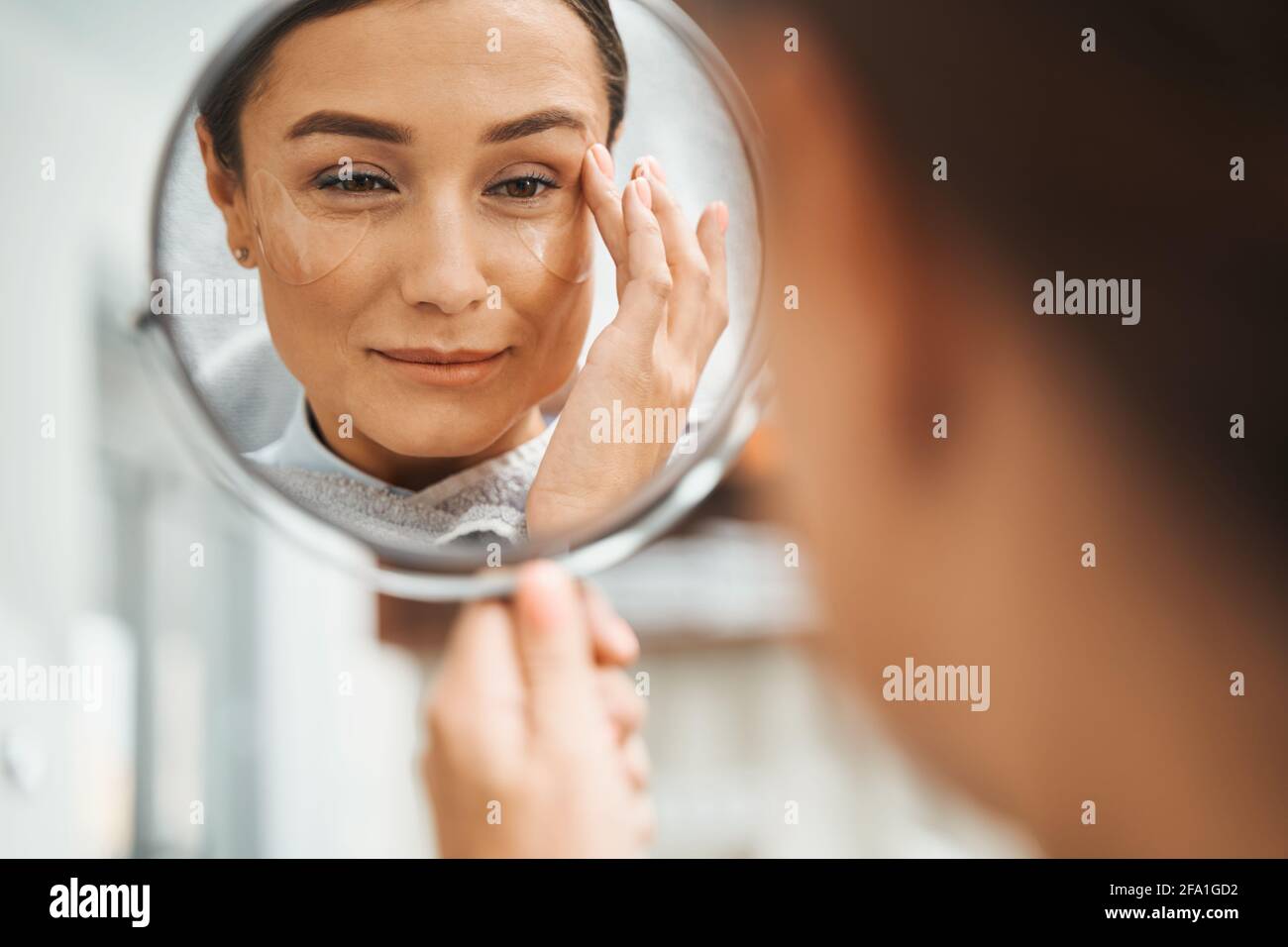 Cliente spa avec un verre à main touchant son visage Banque D'Images