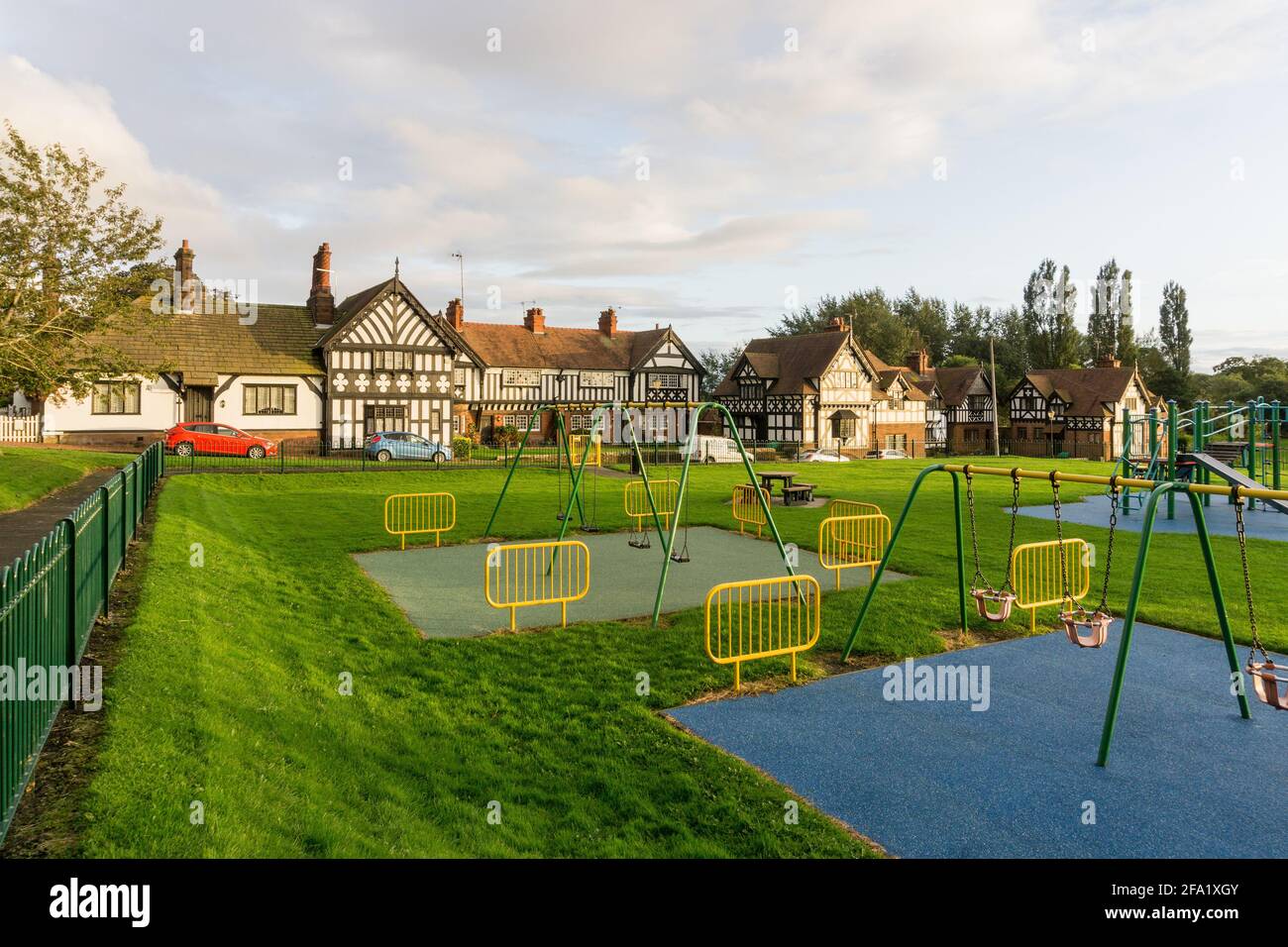 Village vert à Thornton Hough, Wirral, Royaume-Uni; aire de jeux pour enfants au premier plan. Banque D'Images