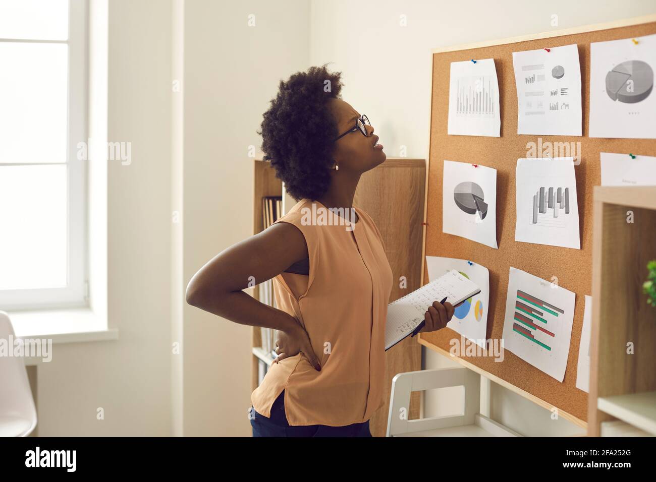 Jeune femme afro-américaine debout près du tableau avec des graphiques et des graphiques Banque D'Images