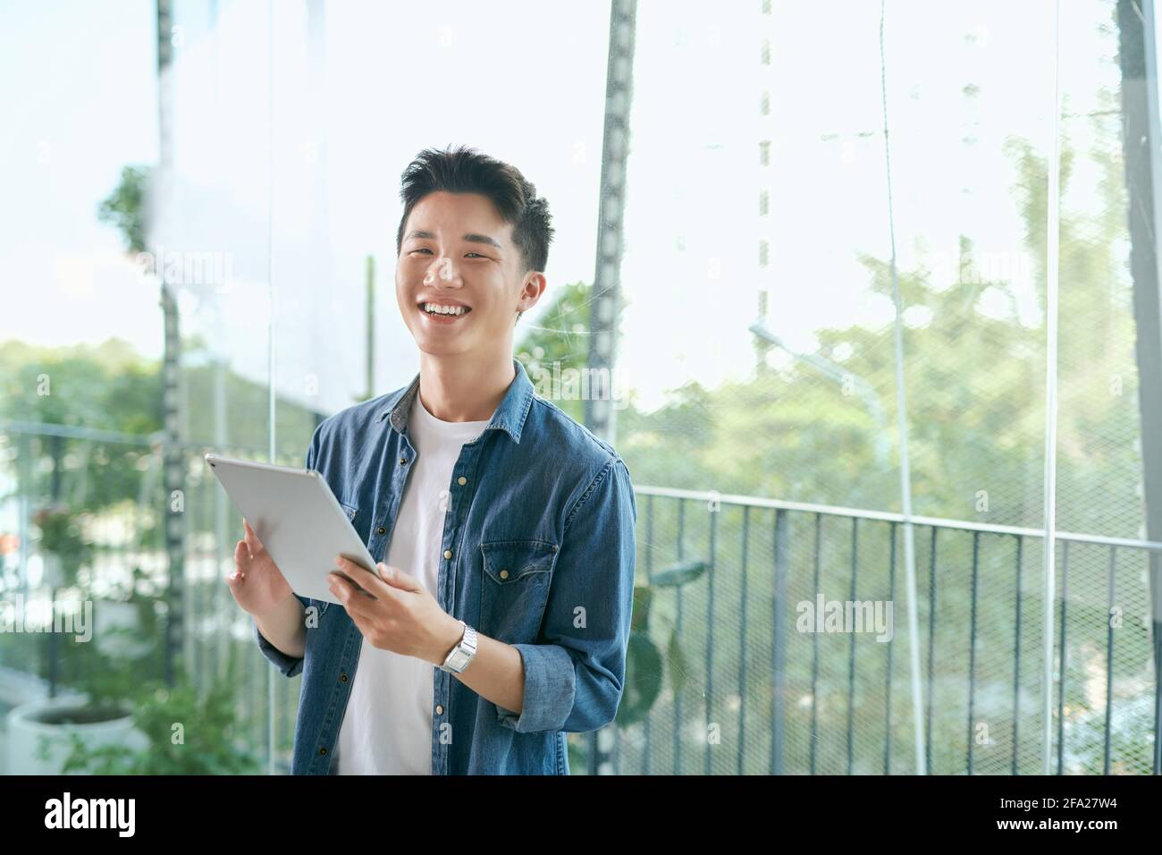 Portrait d'un jeune homme indien souriant confiant holding a tablet et à la recherche dans la distance Banque D'Images