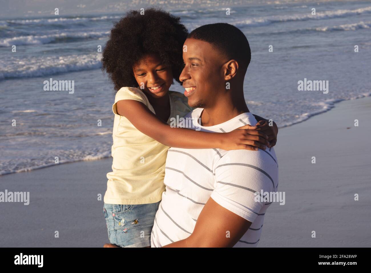 Père et fille afro-américains qui s'embrassent et sourient plage Banque D'Images