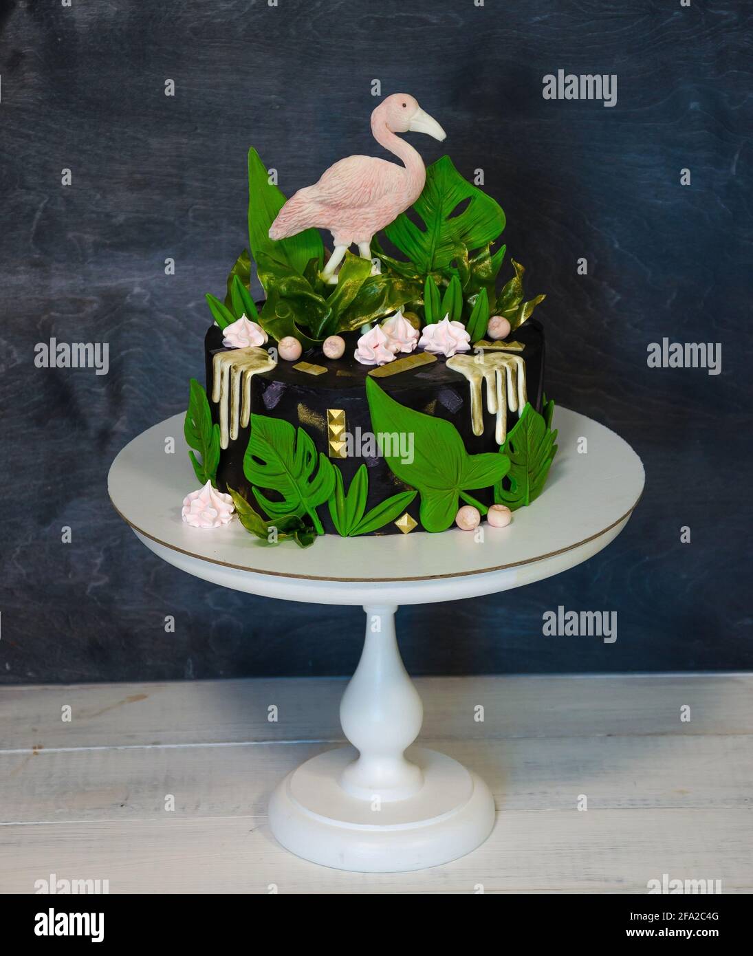 Un gâteau noir à la crème avec du flamant et des feuilles tropicales Banque D'Images