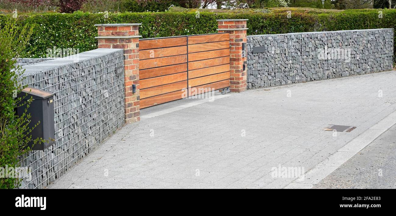 Façade de la maison, mur périphérique de jardin construit à partir de la cage de fils de Gabion rempli de pierre brisée en cage avec des briques et du bois entrées Angleterre Royaume-Uni Banque D'Images