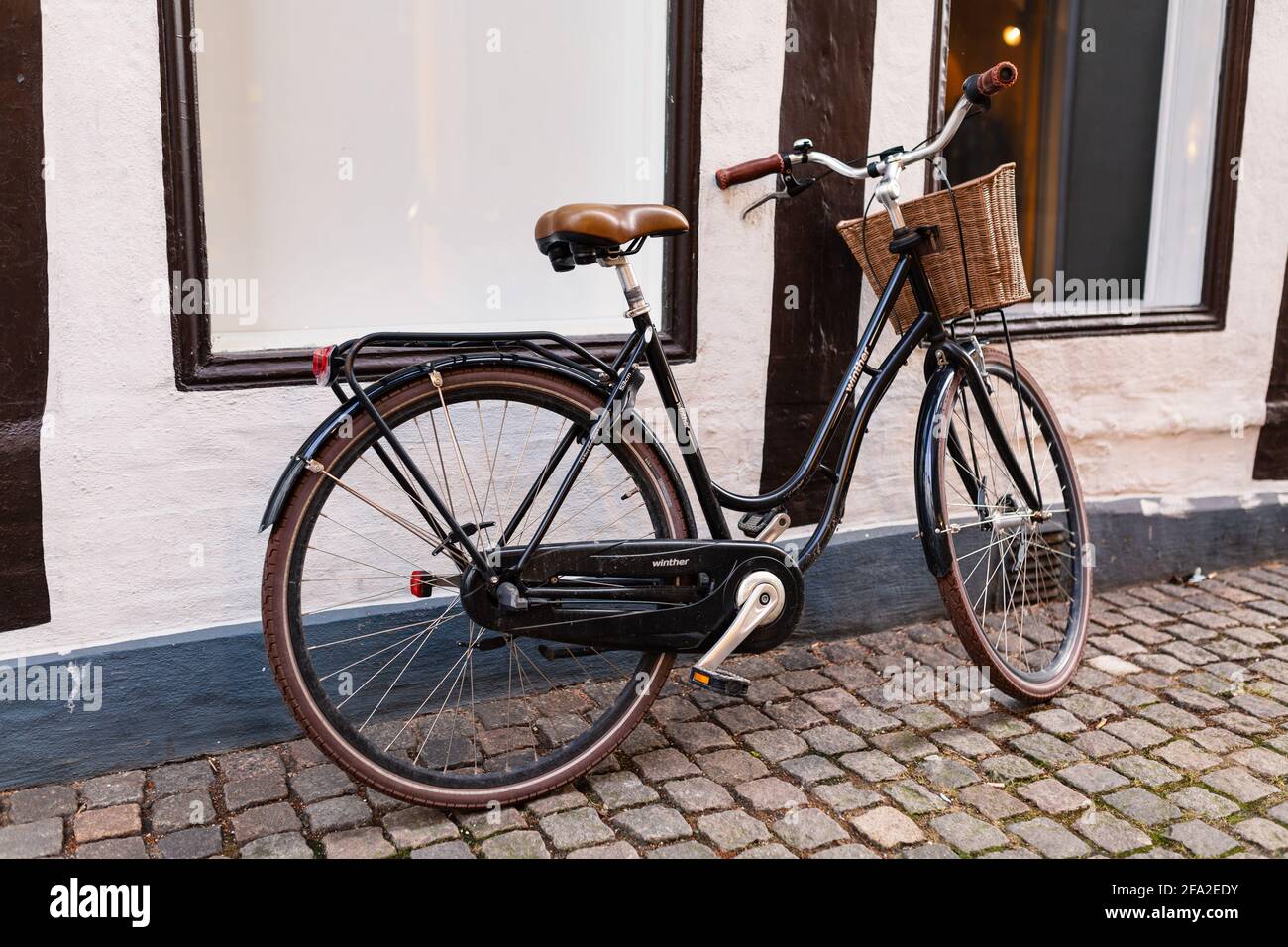 Aalborg, Danemark - février 21 : 2014. Bicyclette femelle avec un panier coincé sur le mur d'un bâtiment. Banque D'Images