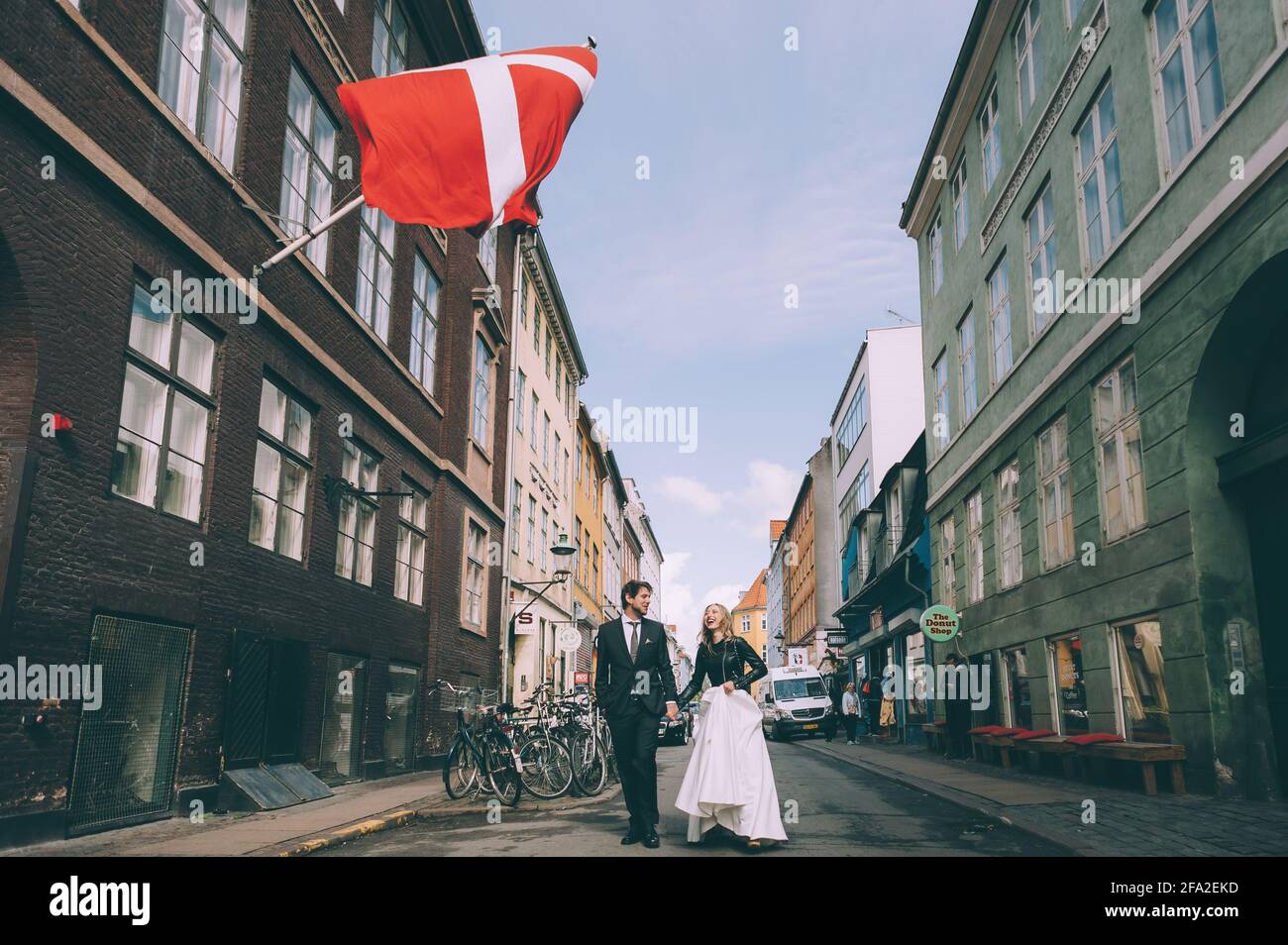 Copenhague, Danemark 11 juin 2019. Couple de mariage marchant dans la rue sur le fond du drapeau du Danemark. Banque D'Images