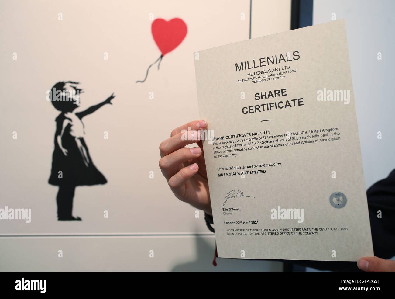 Un certificat d'action est tenu à côté d'une sérigraphie Banksy, Girl with A Balloon, à un prix de 340,000 USD, lors du lancement du portfolio d'art à puce bleue ARTCELS à la Galerie de la Maison des Beaux-Arts (HOFA) dans le centre de Londres. Le portefeuille art offrira une propriété basée sur des actions à l'aide de jetons non fongibles (NFTS) - des jetons numériques liés à des actifs qui peuvent être achetés, vendus et échangés. Date de la photo : jeudi 22 avril 2021. Banque D'Images