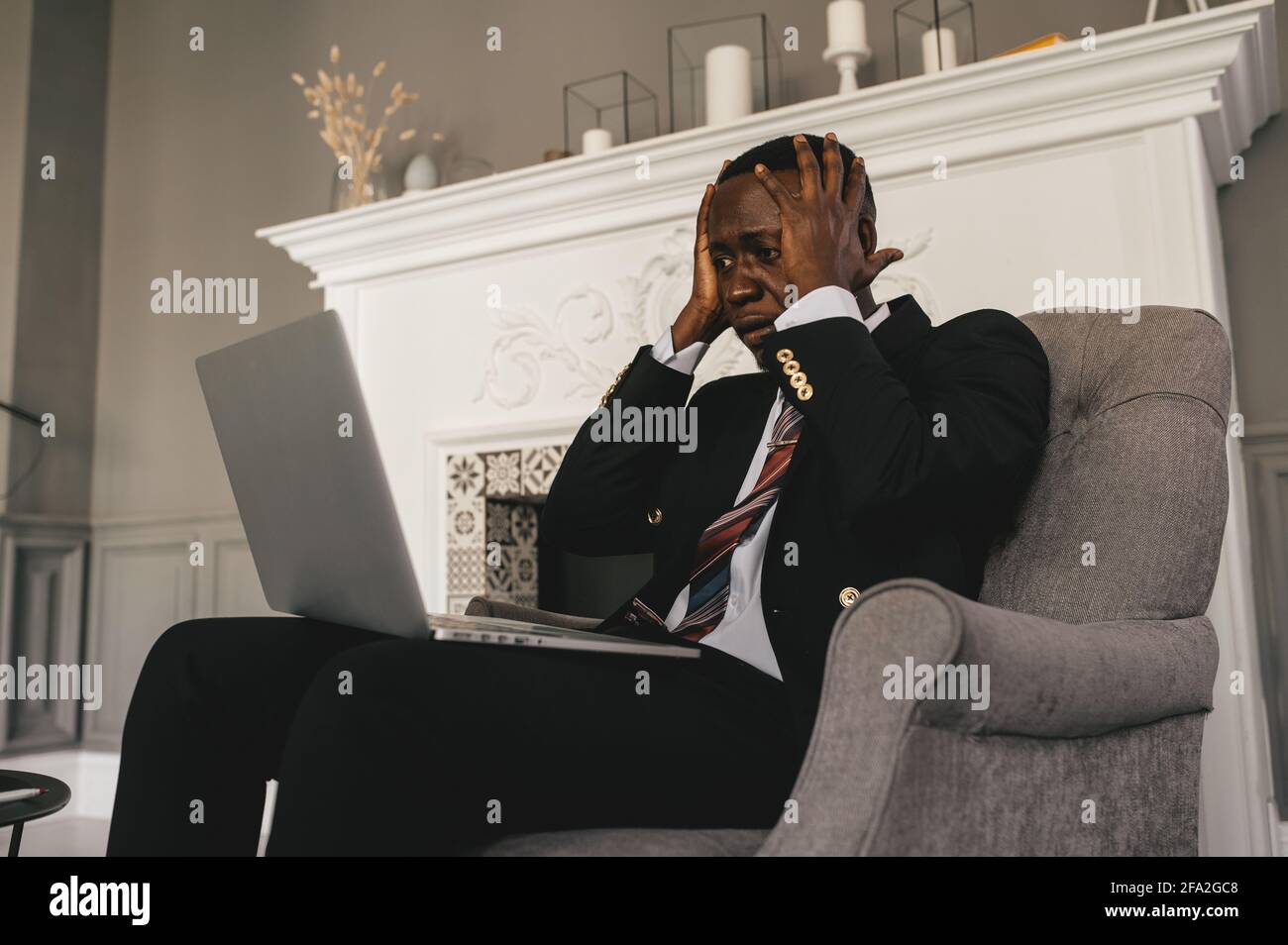 jeune homme noir assis sur une chaise tenant la tête Banque D'Images