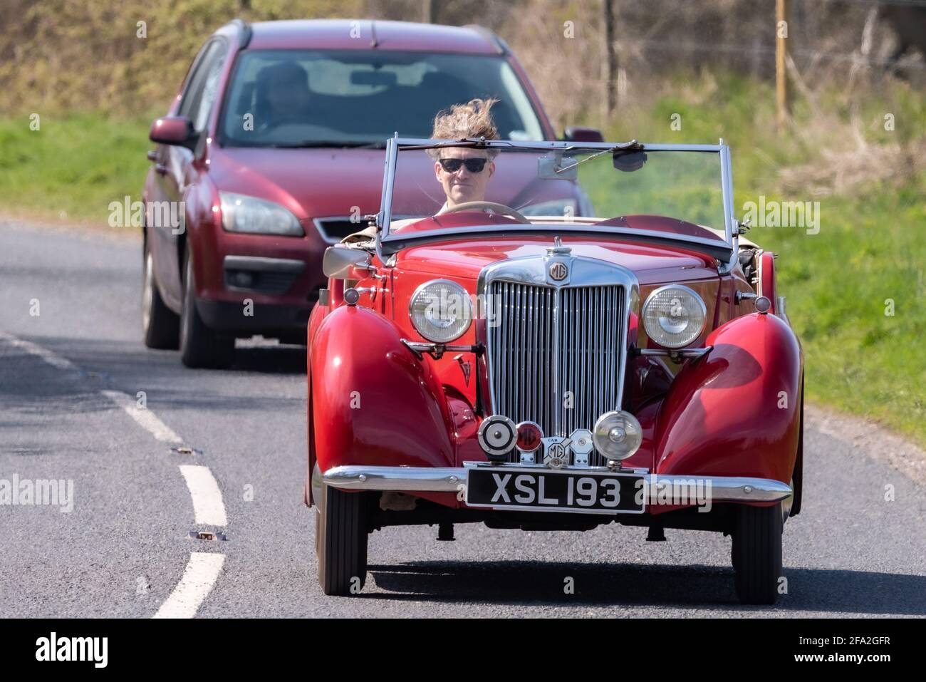 Vent dans la voiture de cheveux, homme conduisant une voiture de sport classique rouge MG, Alresford, Hampshire, Royaume-Uni Banque D'Images