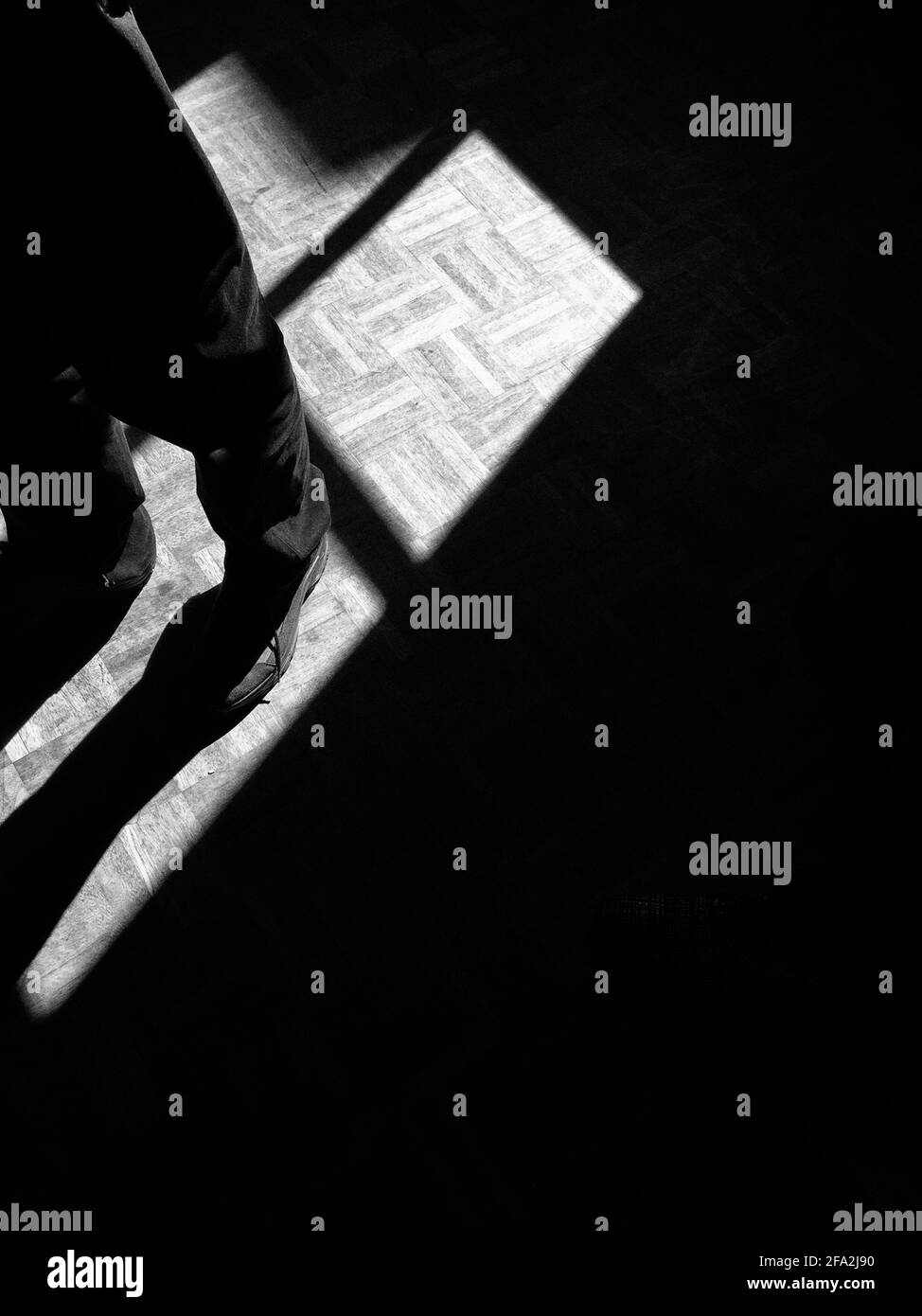 Chaussures et pantalons d'un homme debout dans la lumière en noir et blanc Banque D'Images