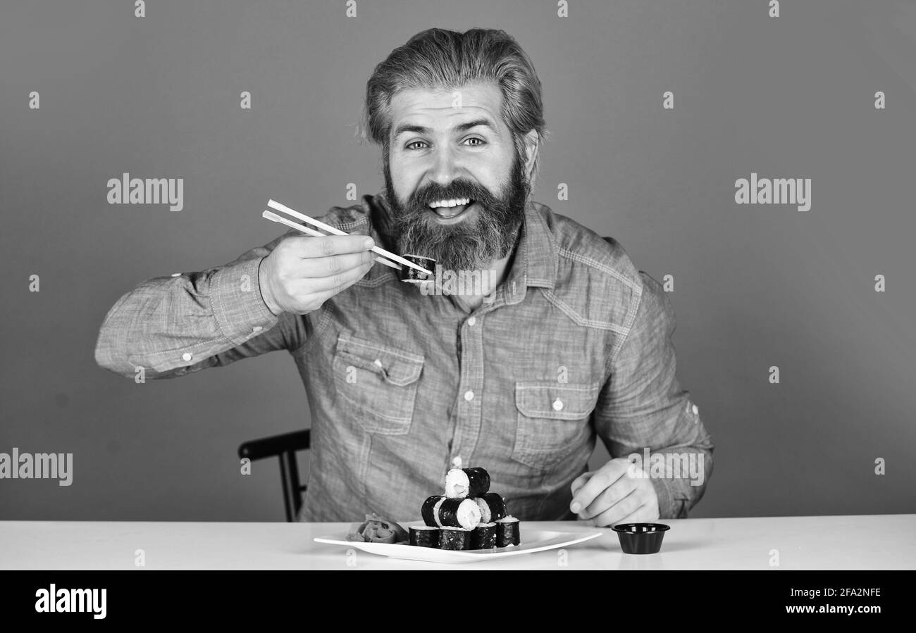 dîner à la maison. hipster mangez des sushis avec des baguettes. délicieux sushi roll. cuisine traditionnelle et saine au japon. plat à sushis japonais. homme mangeant Banque D'Images