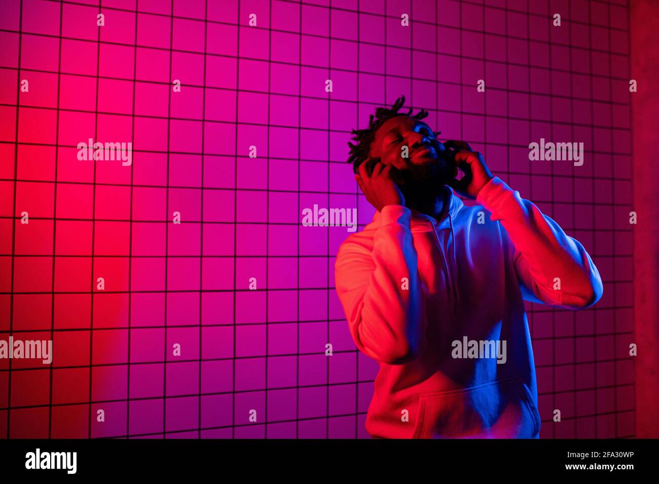 l'homme noir écoute de la musique avec des écouteurs et des danses. Arrière-plan bleu rouge Banque D'Images