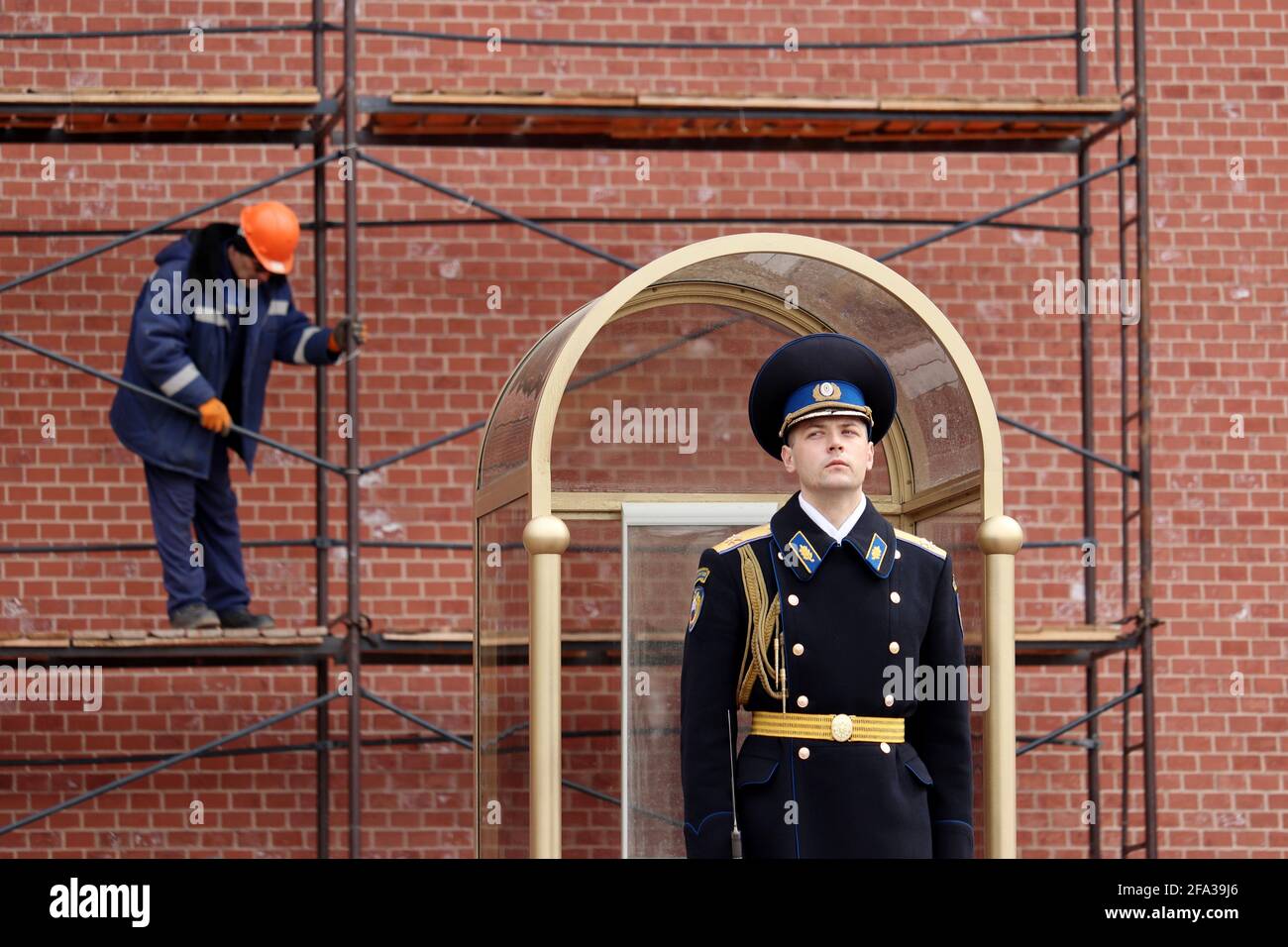 Soldat russe en service sur fond d'ouvrier de construction sur échafaudage. Garde d'honneur du régiment présidentiel lors de la réparation du mur du Kremlin Banque D'Images