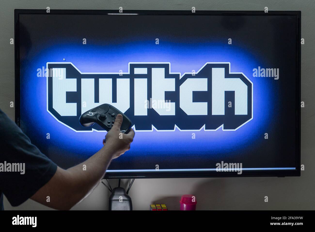 Homme tenant une télécommande de vapeur devant un PC écran de la console  montrant la plate-forme de diffusion en continu de twitch dans laquelle les  gens diffusent en continu plein temps pour