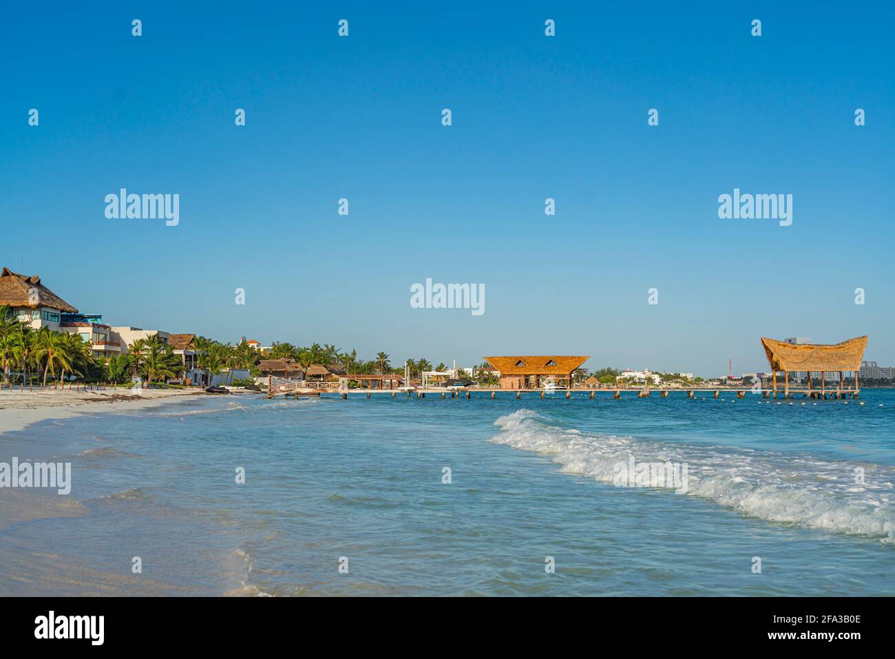 Matin à Ancha Beach à Cancun Mexique avec l'océan calme, fond bleu ciel, huttes à la jetée avec toit de chaume Banque D'Images
